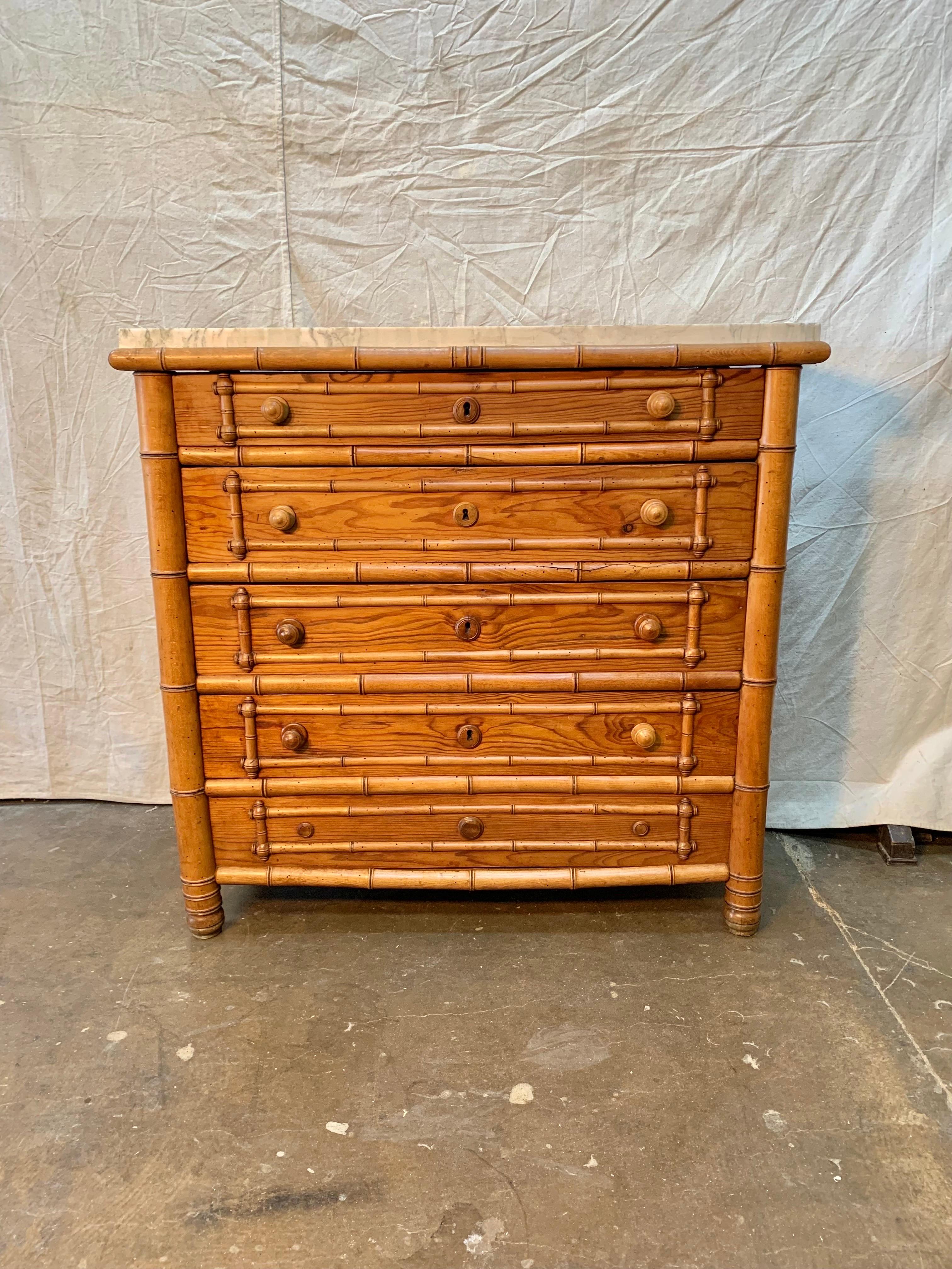 Found in France this Early 20th Century French Pine Faux Bamboo Chest of Drawers features four drawers and a marble top. The hand crafted piece has beautiful graining and color in the wood and a lovely marble top with white and grey hues. The four