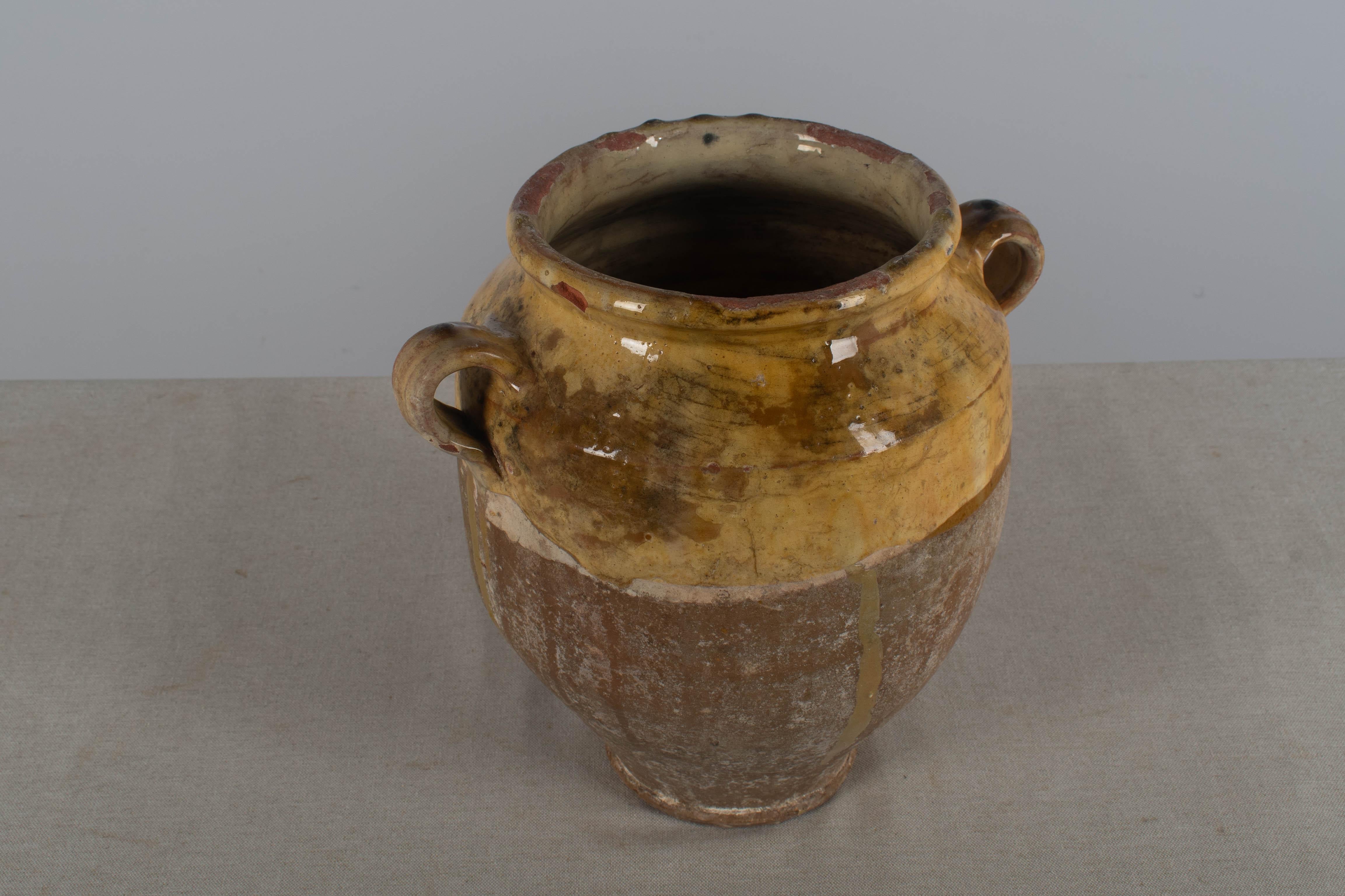 An Early 20th  century  earthenware confit pot from the Southwest of France with traditional yellow glaze.  Chips and losses to glaze,  near top.   These ordinary earthenware vessels were once used daily in the French country home and have beautiful