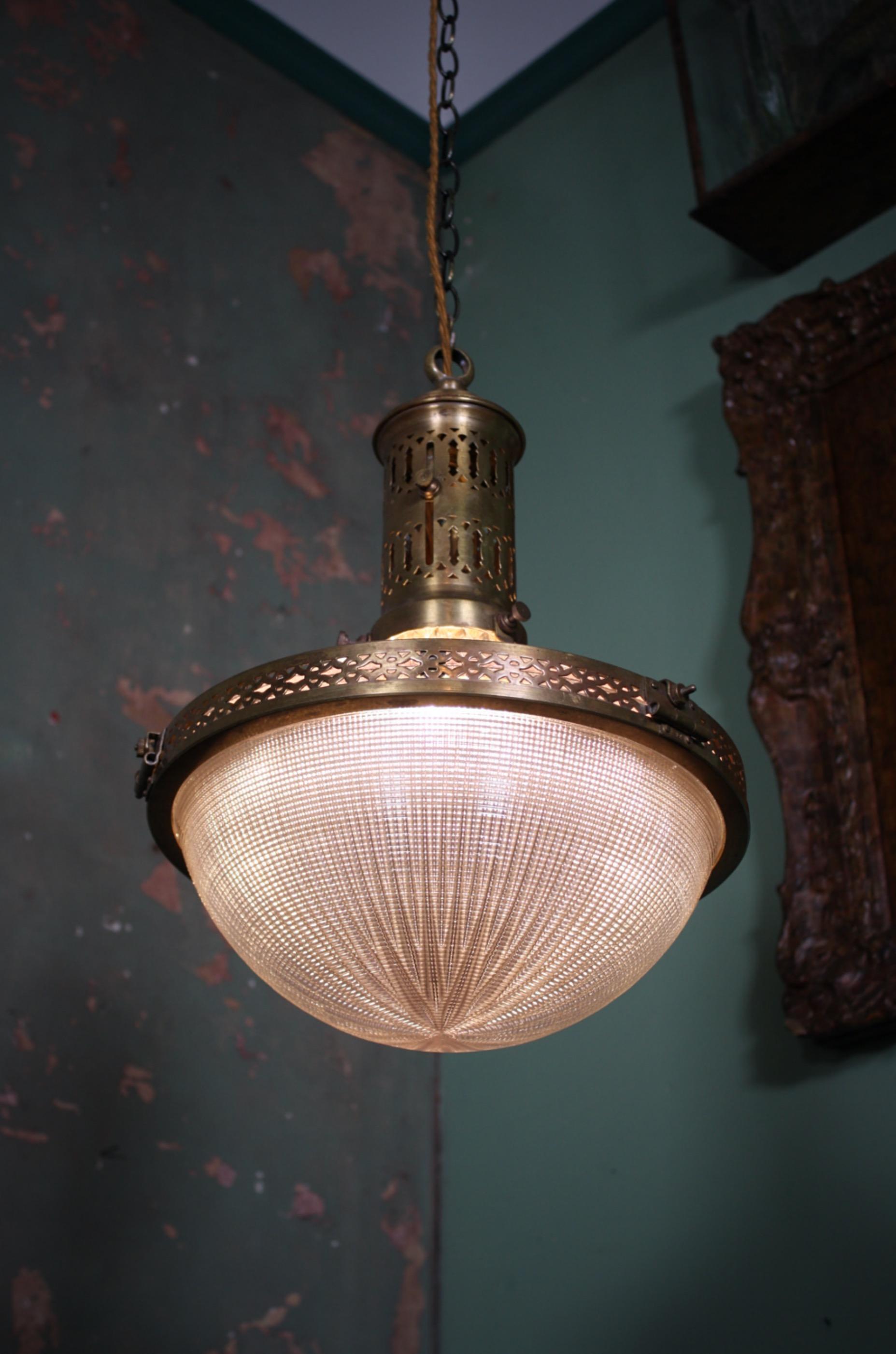 A pristine and original early 20th century French Holophane pendant, a decoratively pierced brass cage holds two section of prismatic glass. The glass holds a light violet hue, a very rare and large example.

All metal sections have age related