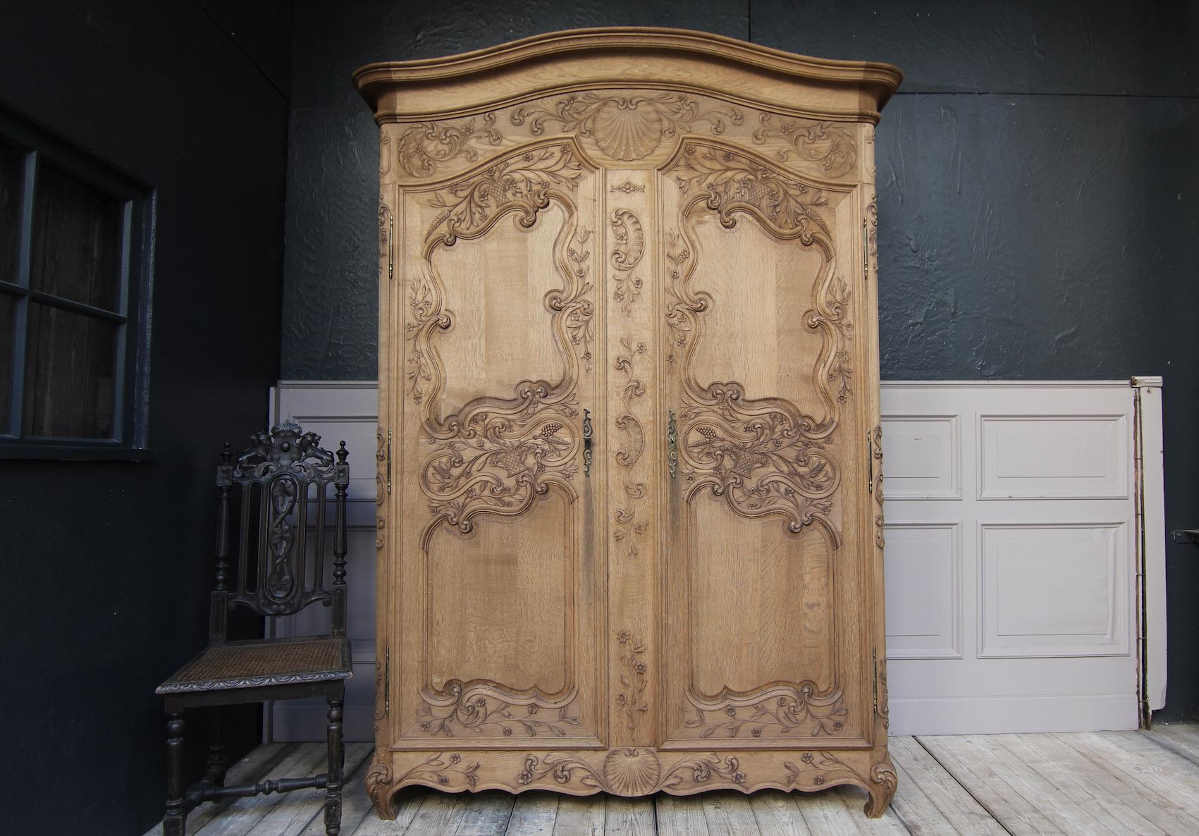 Early 20th century French Armoire in stripped oak. 
A two-door side coffered body with rounded corners and profiled curved cornice. Richly carved floral and rocaille motifs. Doors with carved panels hung on external fitches.

Both doors and the
