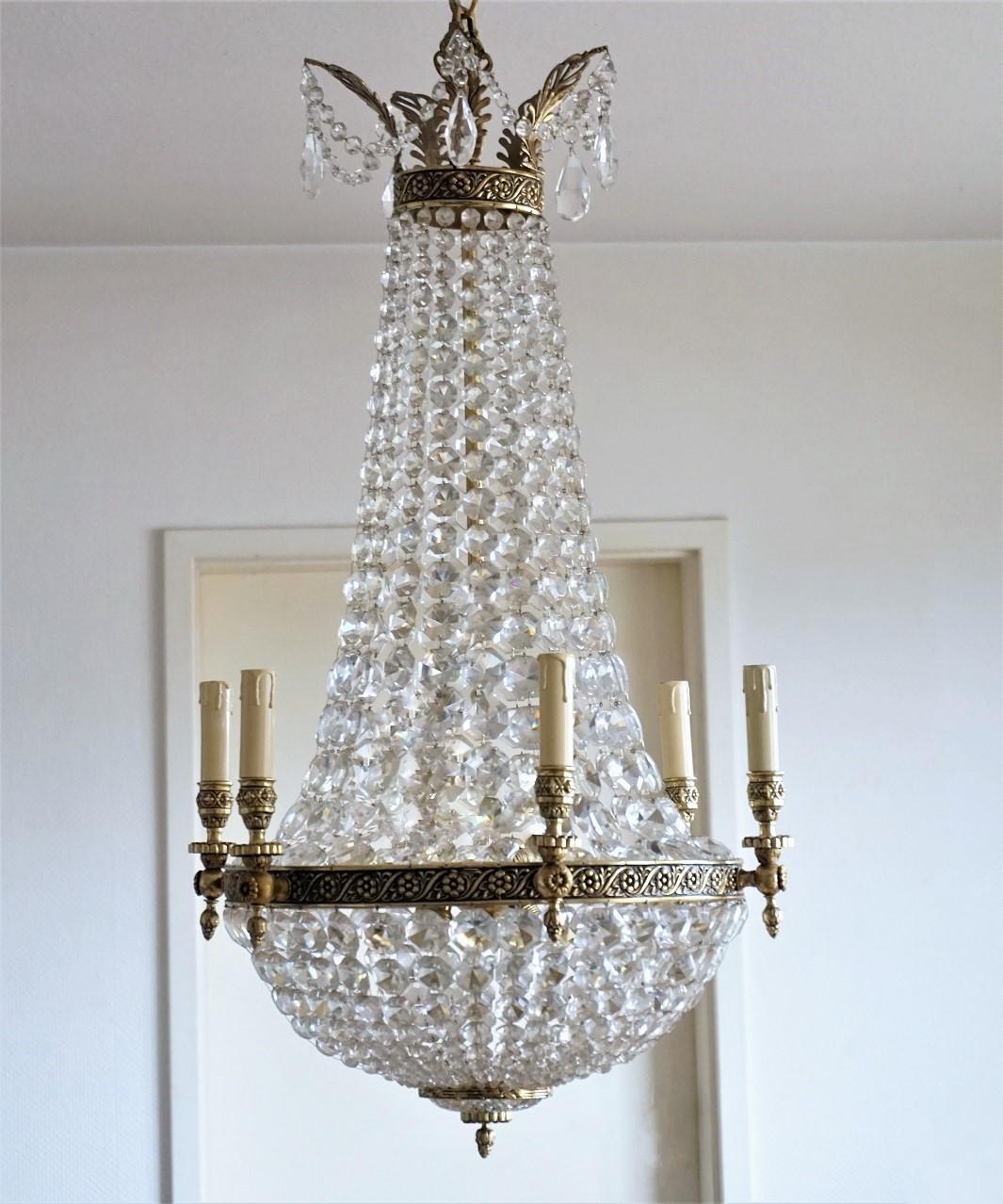 A very elegant Regency style faceted crystal twelve-light chandelier, France, 1900-1910. Solid bronze central ring with six lamp arms, crown shaped top with large crystal drops. The chandelier has been hand polished and cleaned to its original
