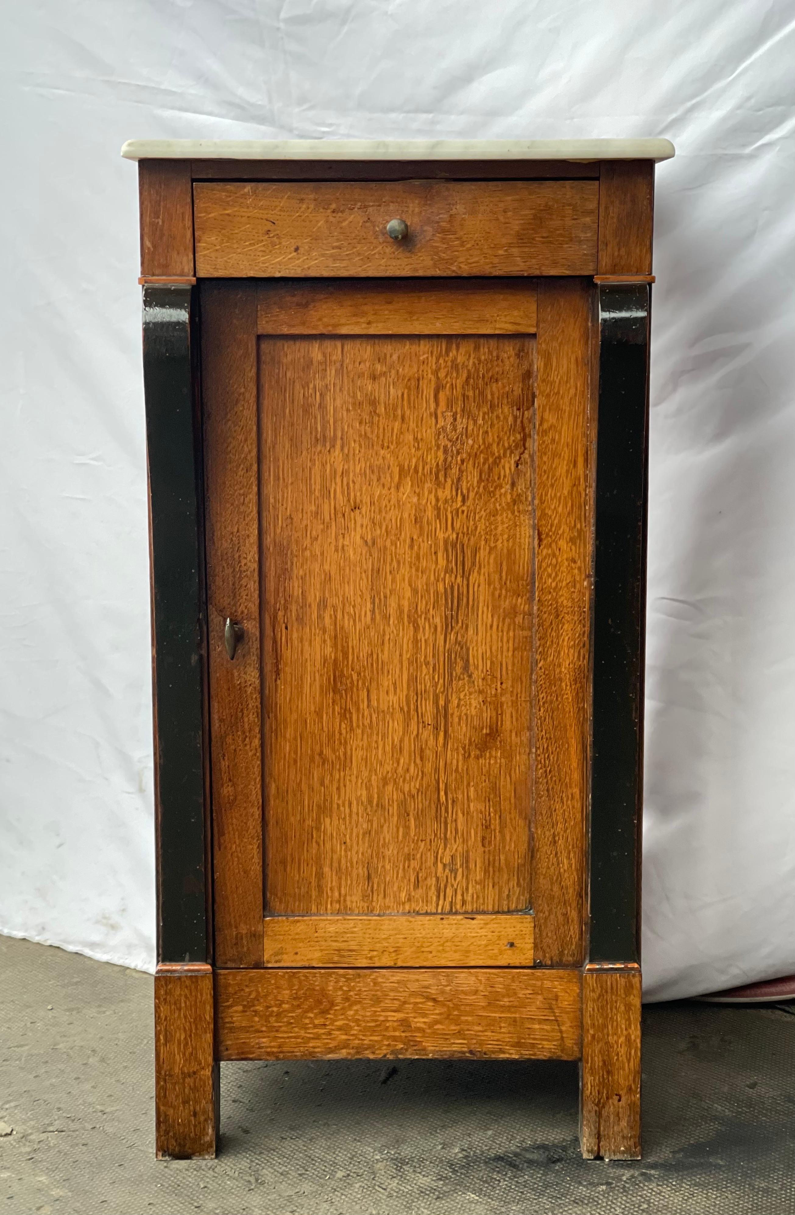 A stately restoration period cabinet or nightstand in walnut. With a slim profile and geometric simplicity of form, this little piece will fit in beautifully with a variety of styles. A plinth base with flat sides and unembellished marble top let