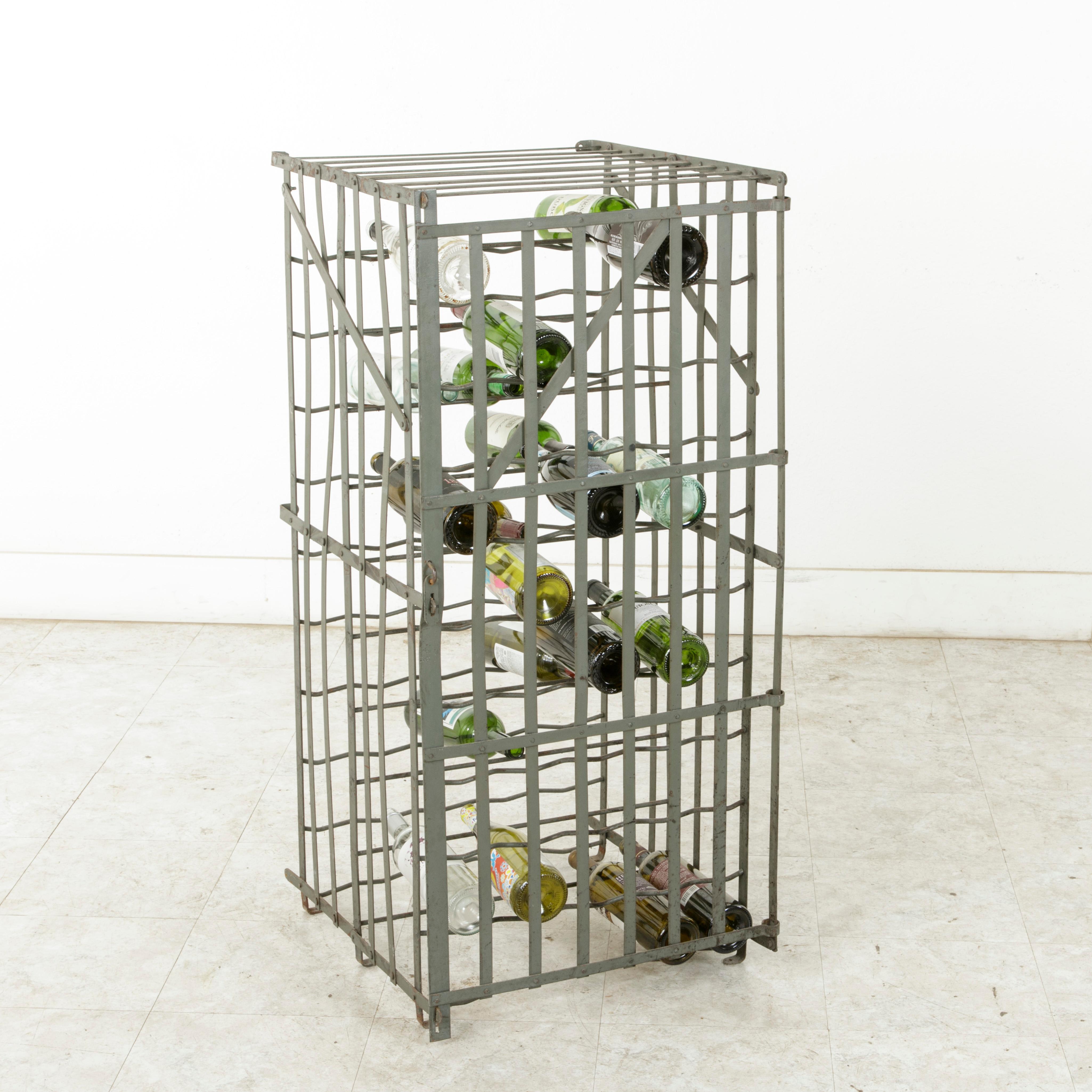 Originally used in a French wine cellar, this riveted iron wine cage from the early twentieth century holds up to 80 bottles. This wine rack may either be bolted to the wall or remain freestanding, and it may be locked with a padlock. Smaller in