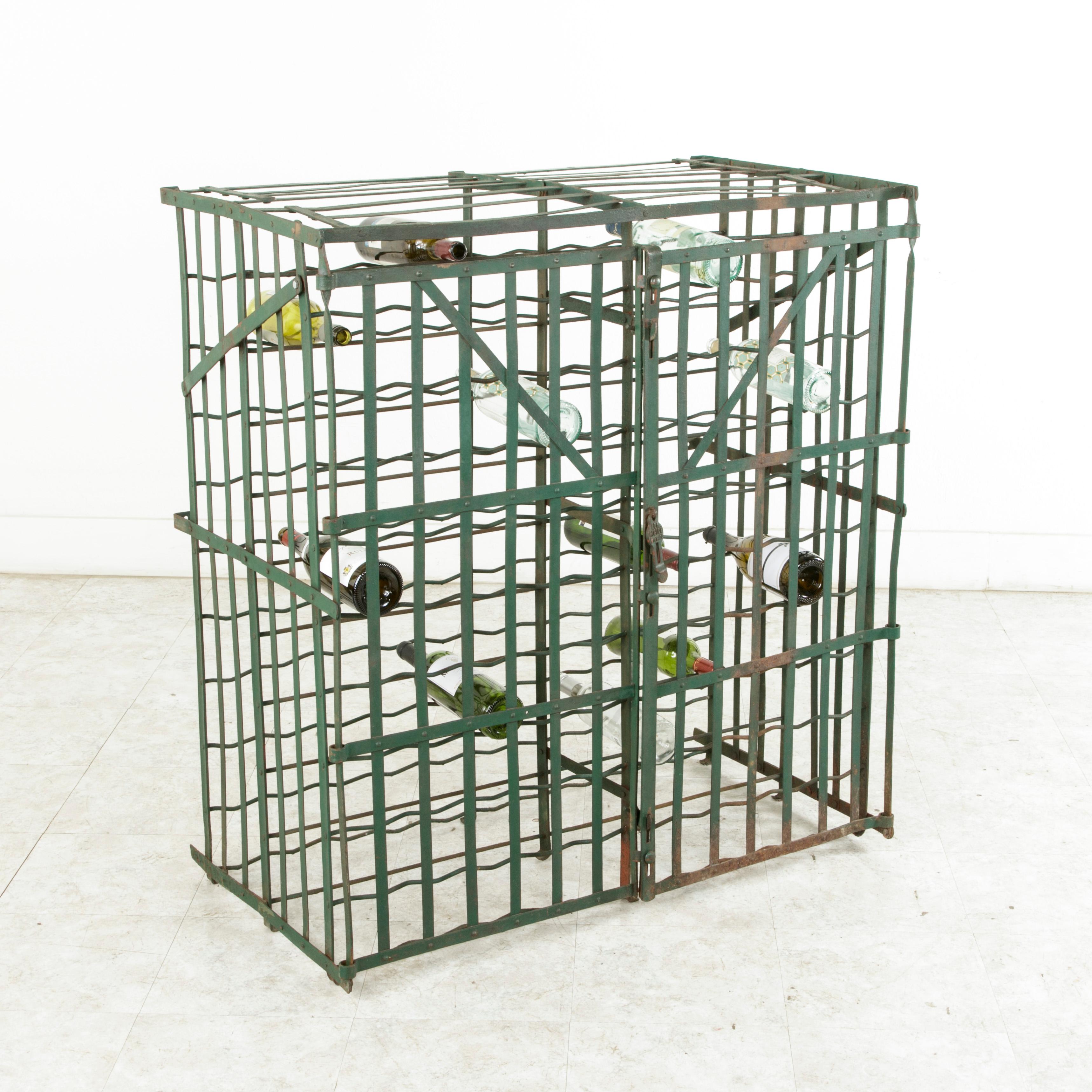 Originally used in a French wine cellar, this riveted iron wine cage from the early twentieth century holds up to 200 bottles and is painted in a dark green. The lock plate that slides over the ring where a padlock can be secured is marked Fer