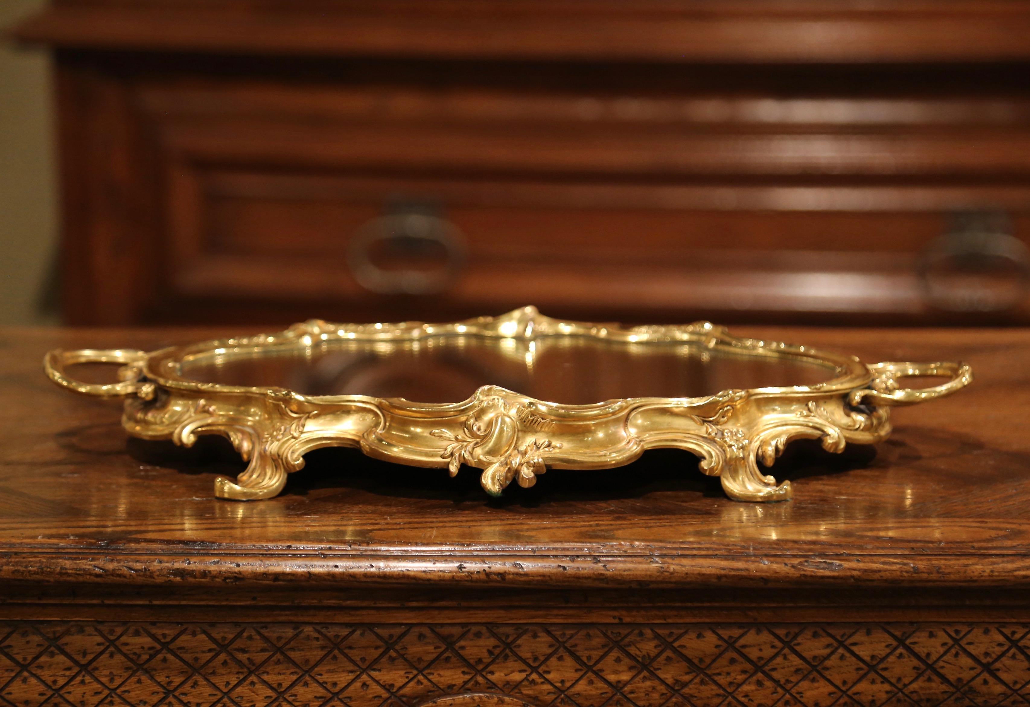 This elegant antique Louis XV gilt table tray was created in Paris, France, circa 1920. Oval in shape, the bronze plateau stands on four acanthus leaves feet over a scalloped edge decorated with floral and scroll motifs. The center piece is