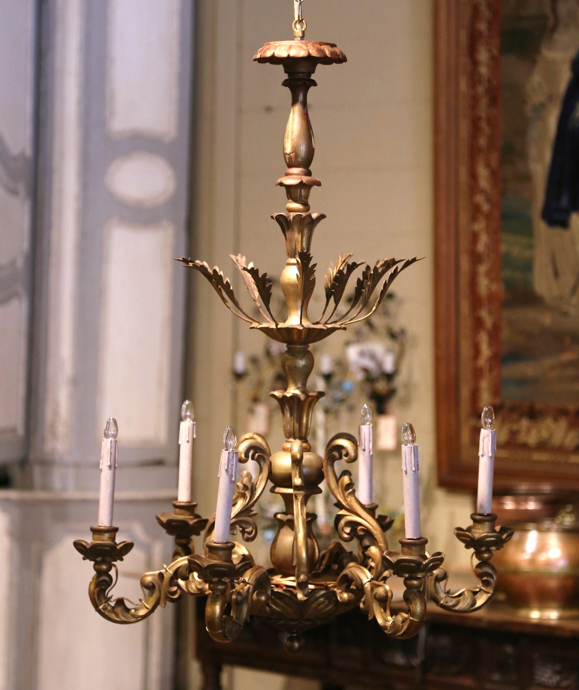 Decorate a dining room, breakfast room or entry with this antique gilt wood chandelier. Hand carved in France circa 1920, the fixture is characterized by its intricate detailing and elegant curves. The central stem features a tall, tapering design