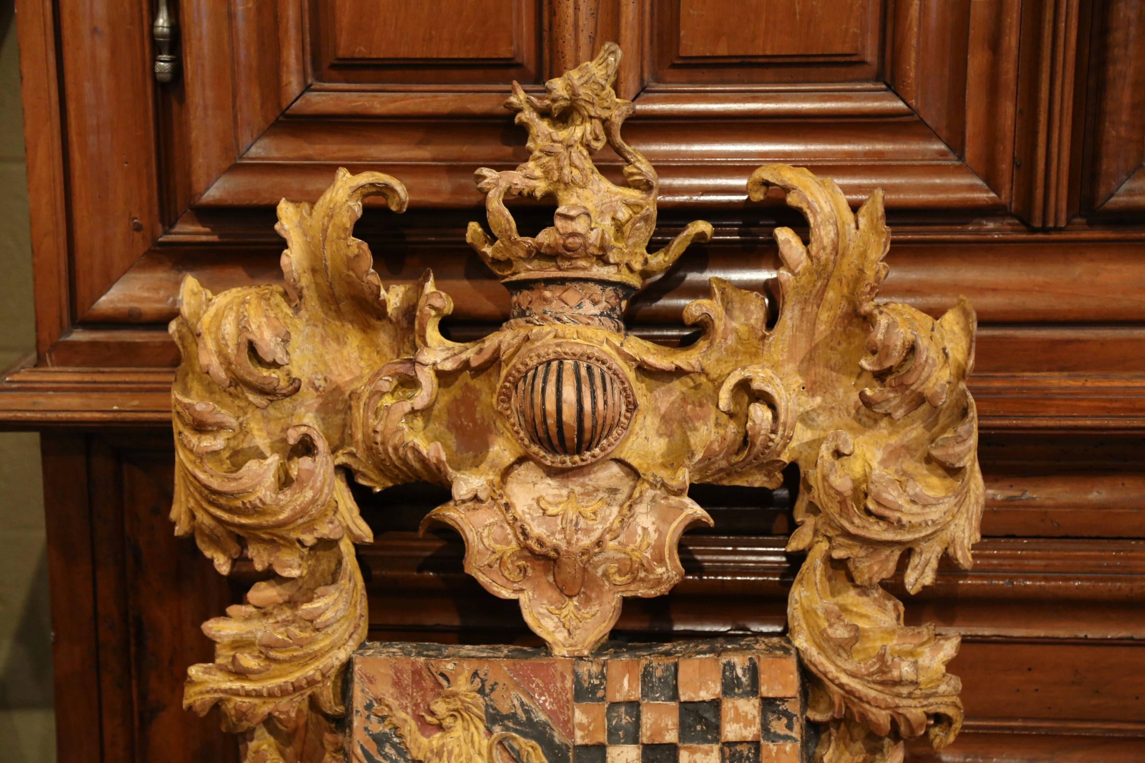 Embellish your wall with this large antique, medieval crest. Hand-carved in France, circa 1920, the Rococo, painted shield has a crown at the pediment with helmet from a suit of armor, decorative foliage motifs on both sides. The centre part
