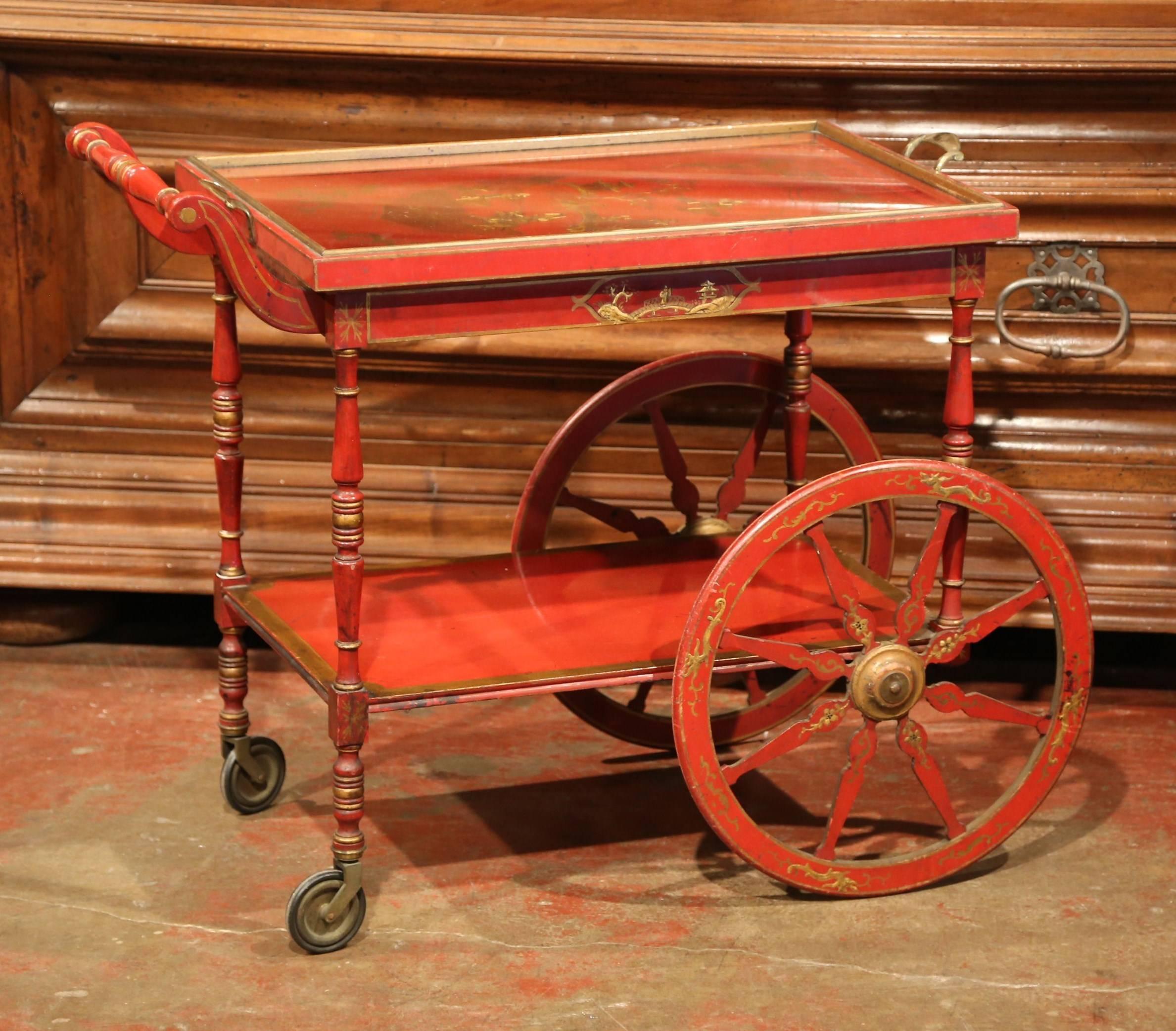 Created in France circa 1920 and rectangular in shape, the cart stands on large front wheels and is painted in red with gilt accents; the piece features decorative chinoiserie embellishments with hand painted Chinese figures, tree and leaf decor.