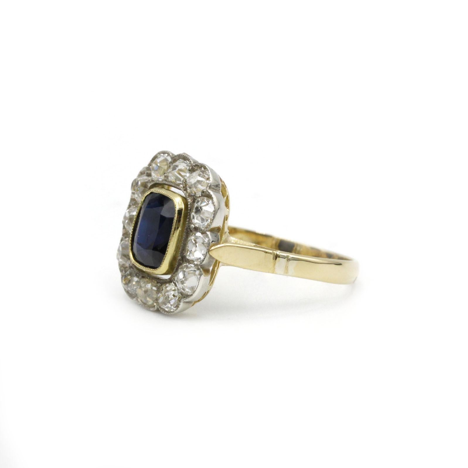 An enchanting early 20th-century French “marguerite” (daisy) cluster ring, painstakingly crafted at the turn of the Belle Époque into Art Nouveau transition. At its heart sits a deep cornflower-blue cushion-cut sapphire of approximately 1.20 carats,