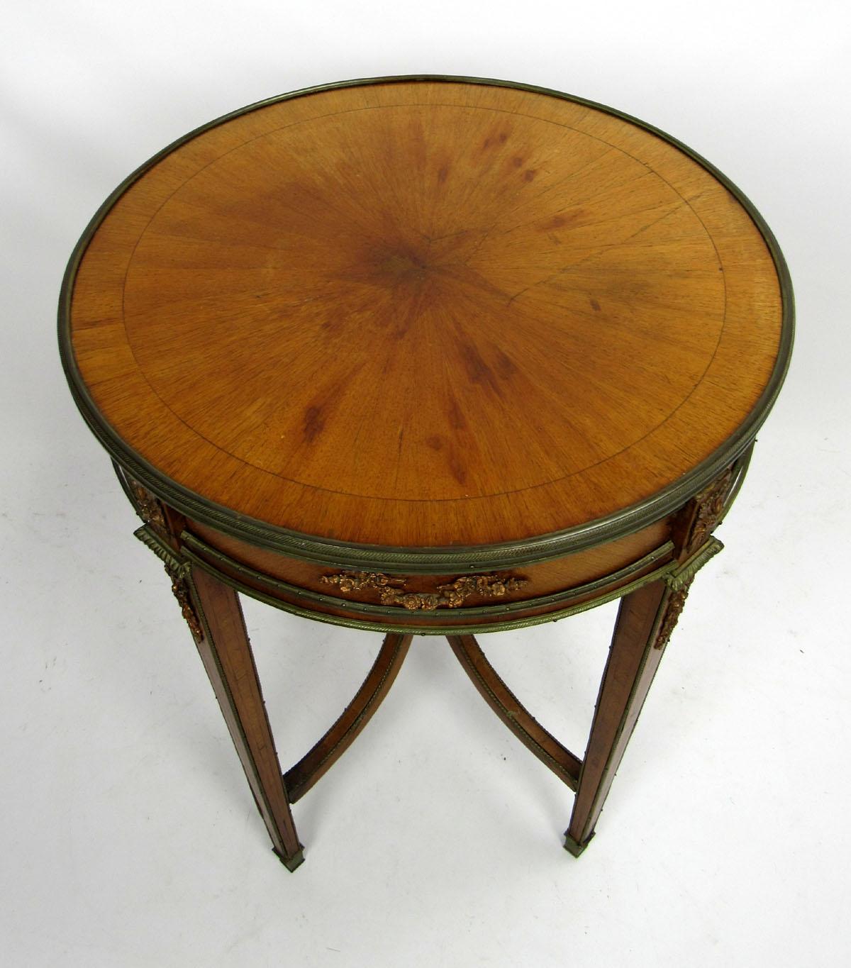 Early 20th century French round side table in a pale wooden finish with an inlaid central star, ormolu fittings with a copper-colored patina, and unique upraised stretchers topped with a crown gallery.