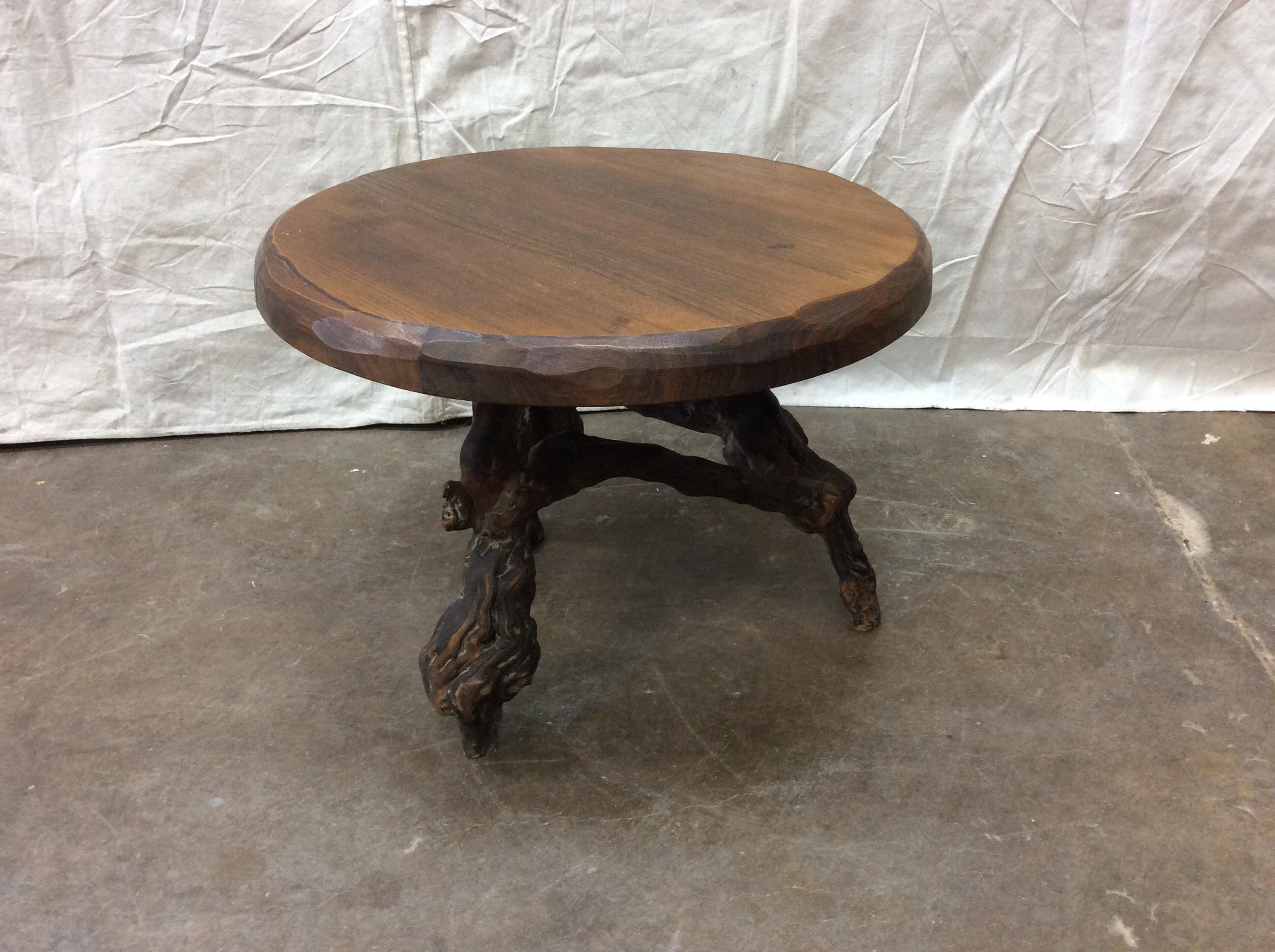 A French small sized coffee or side table with grapevine base from the early 20th century. This table features a round-shaped wood slab top with carved scalloped edges, with a natural grapevine base. The grapevine base is made up of triangulated