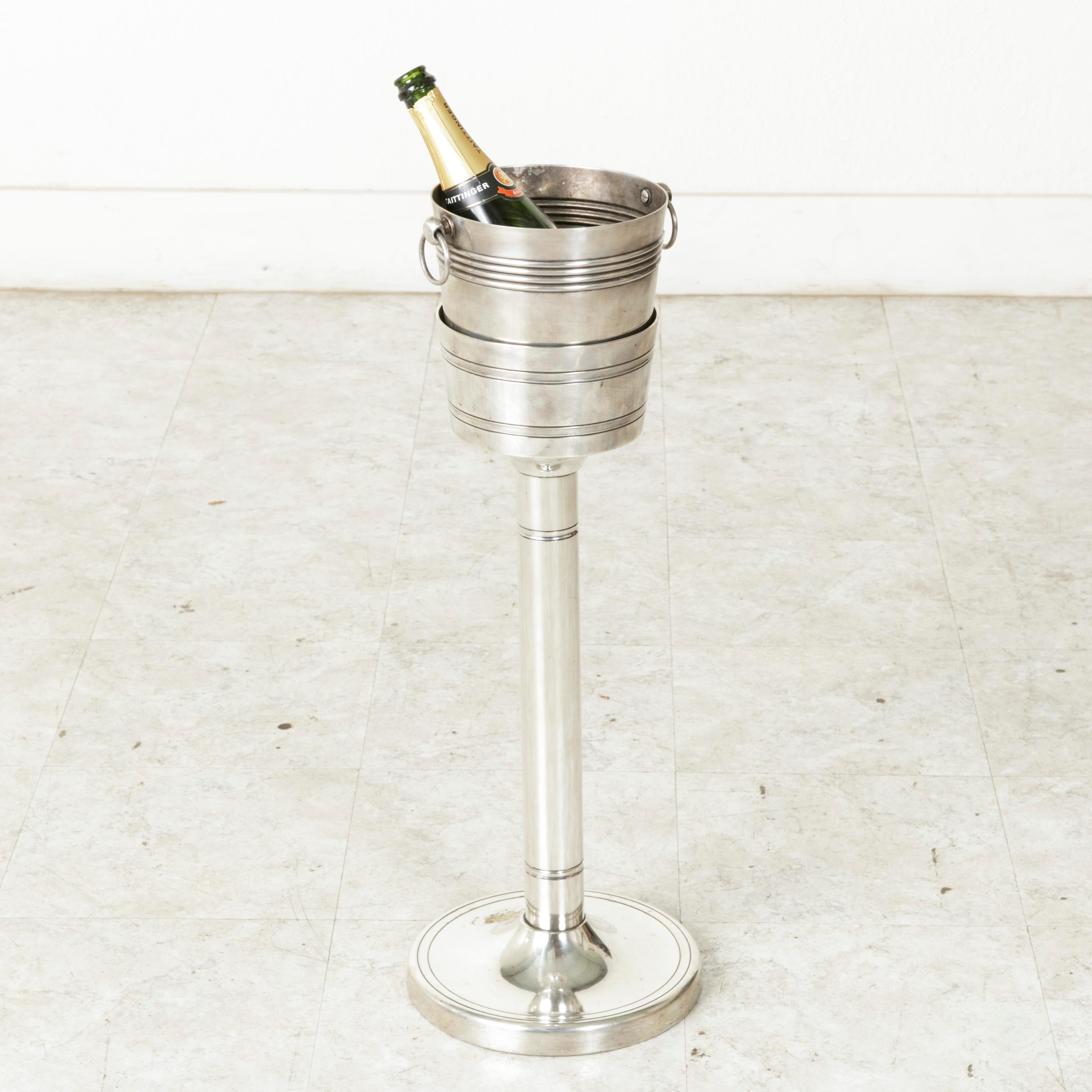 Originally used in a French restaurant to be placed beside a dining table, this silver plate champagne stand contains its original corresponding silver plate bucket. Simple designs of banding encircle the bucket and stand. The stand is 24 inches in