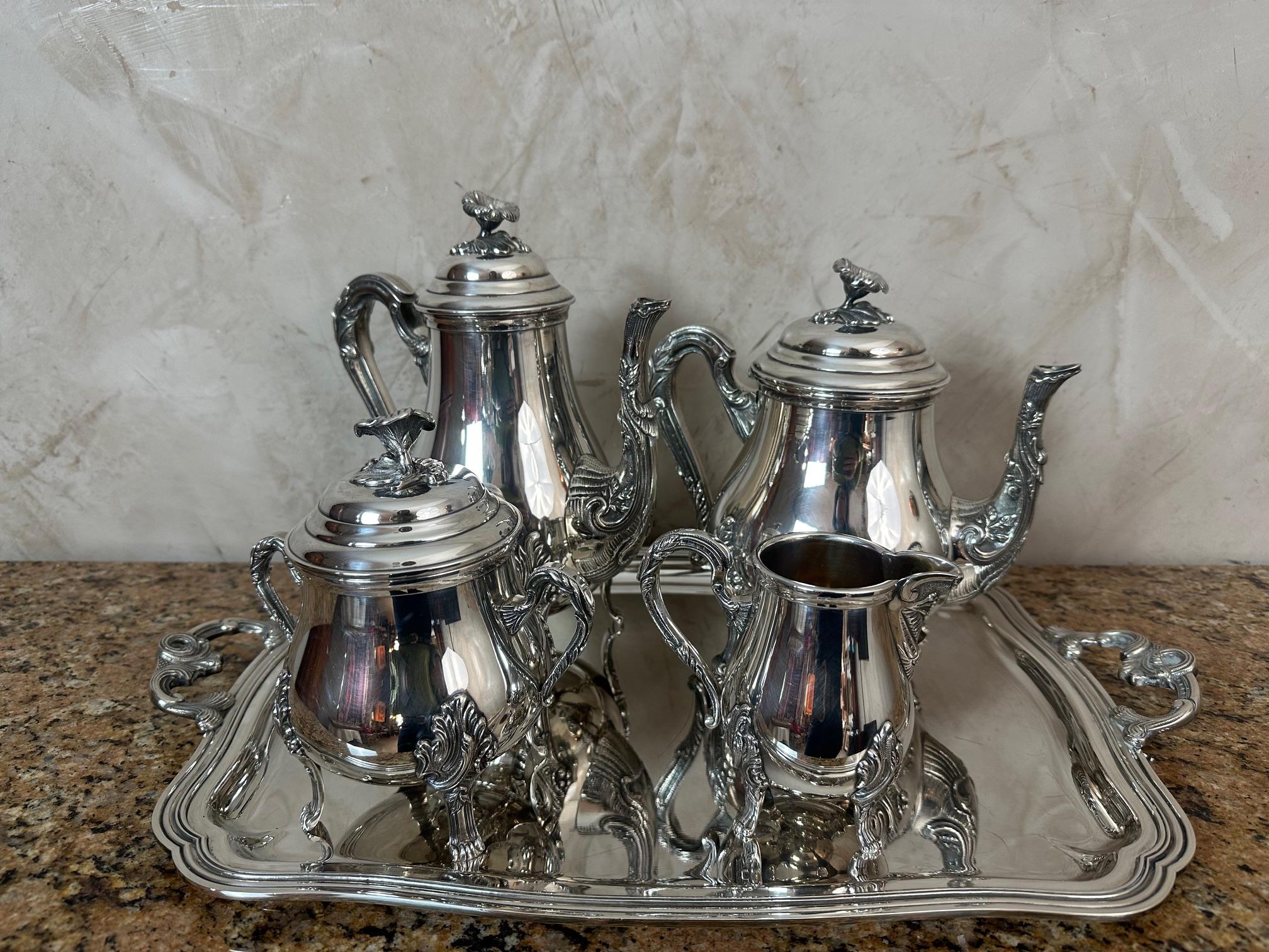 Superbe service complet en métal argenté datant du début du XXe siècle de style Rocaille, composé d'un plateau rectangulaire avec poignées, d'une cafetière, d'une théière, d'un pot à lait et d'un sucrier couvert.

Chaque pièce repose sur de gracieux