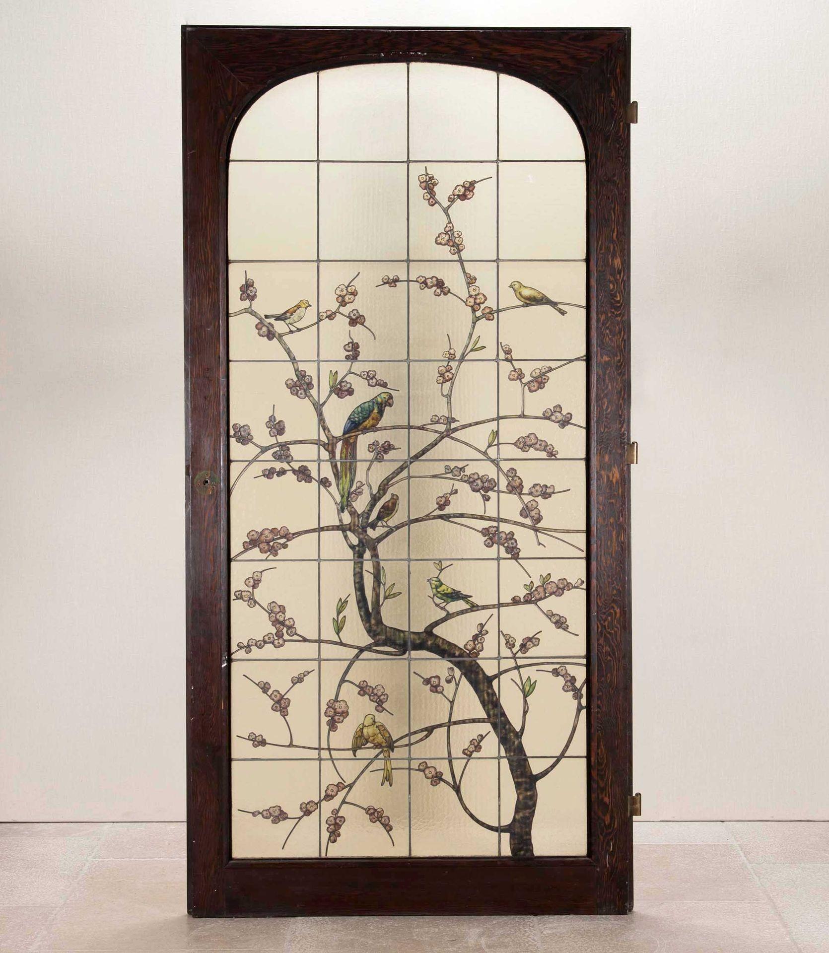 Una hermosa puerta de madera noble acristalada de principios del siglo XX con paneles de vidrieras de inspiración japonesa que representan  un loro y otros pájaros sentados en ramas de estilizadas flores.
