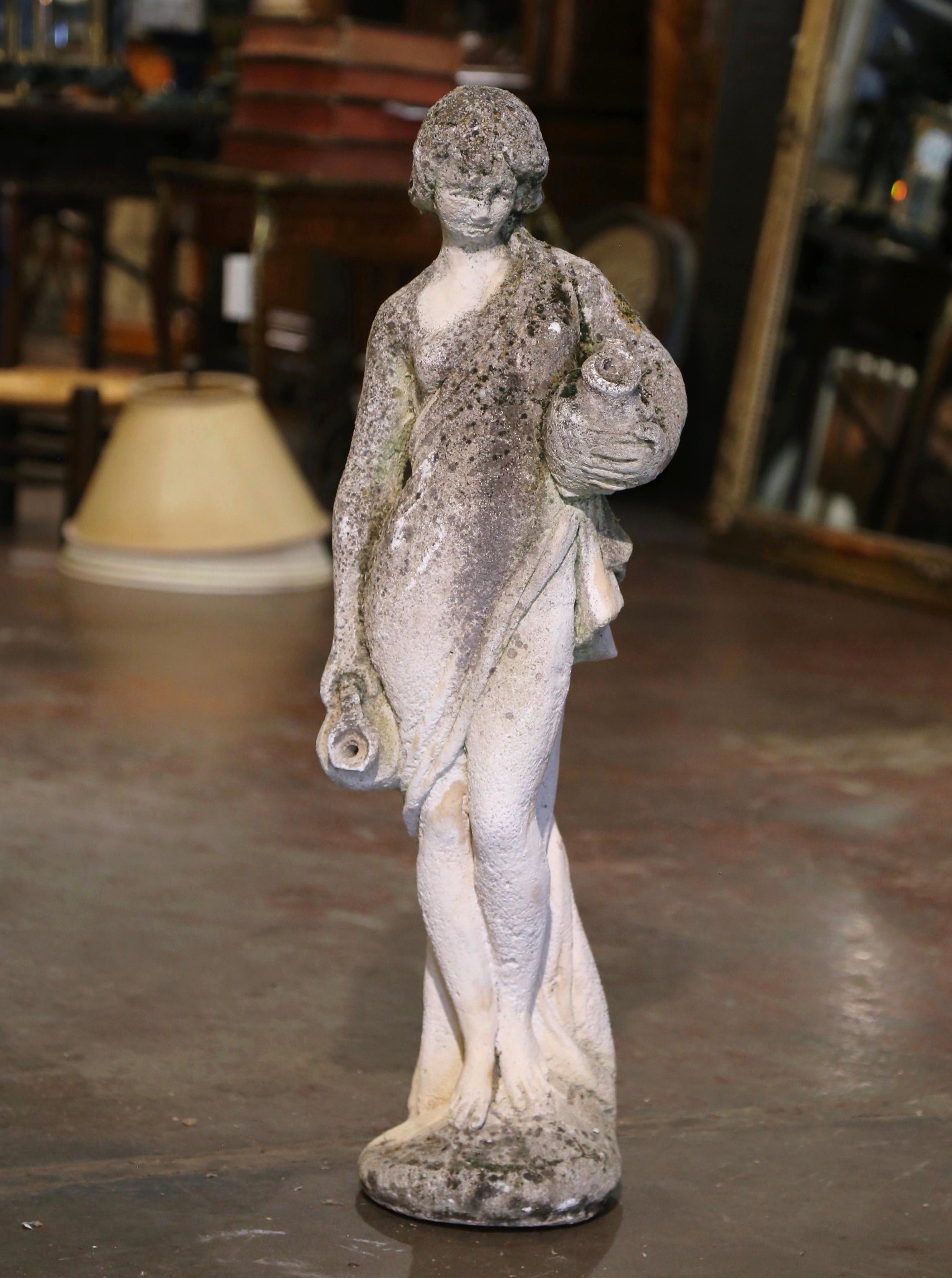 Decorate a garden or patio with this elegant antique outdoor statue. Made of cast stone in France circa 1920, the figure stands on a round base and depicts a young woman standing gracefully while holding two water jugs, the figure is draped in a