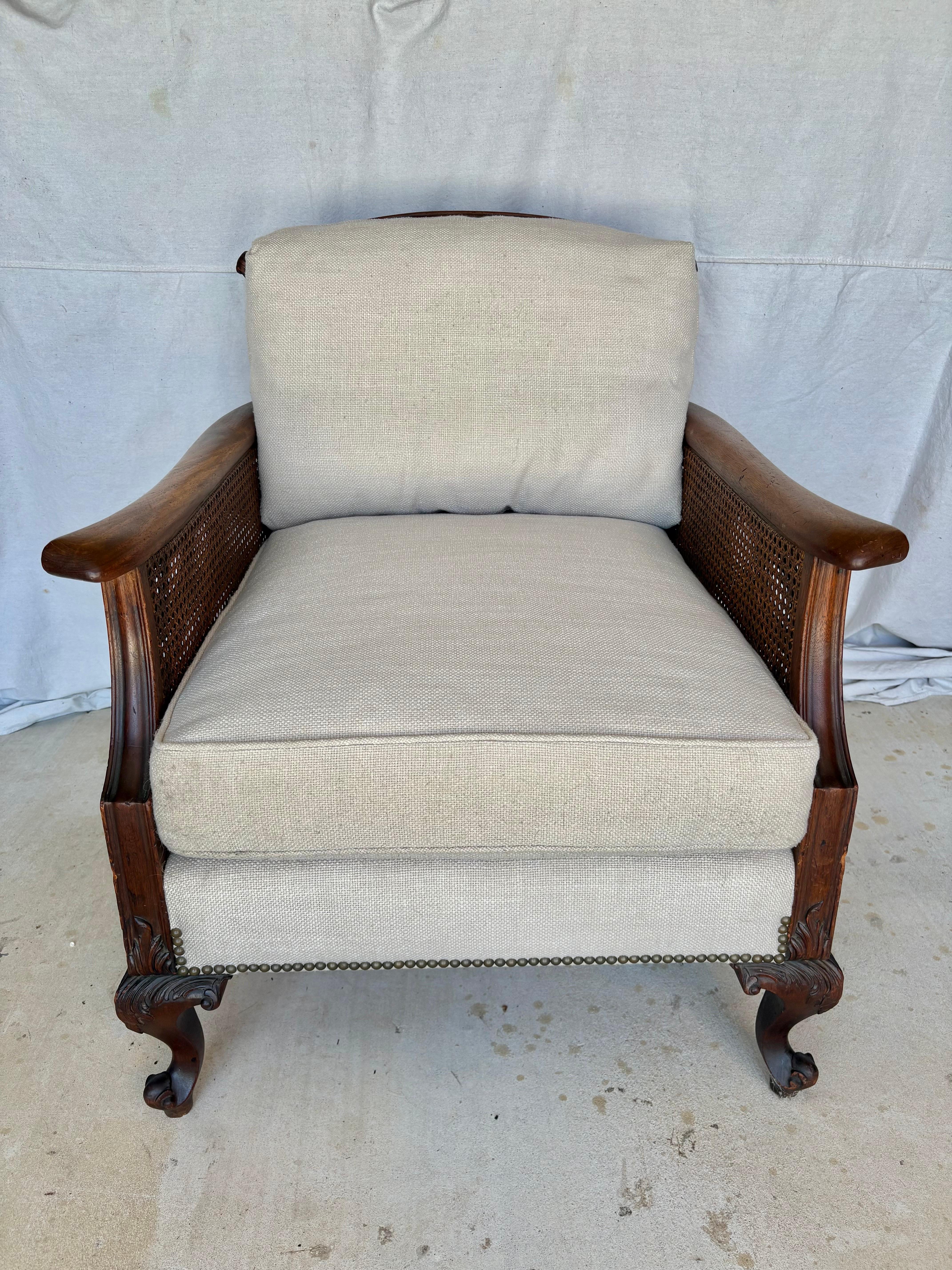 Cette chaise longue de style français du début du XXe siècle a été fabriquée au début des années 1900 en noyer et en rotin. Le fauteuil présente une structure en noyer avec un dossier canné et des côtés à double cannelure. Reposant sur quatre pieds,