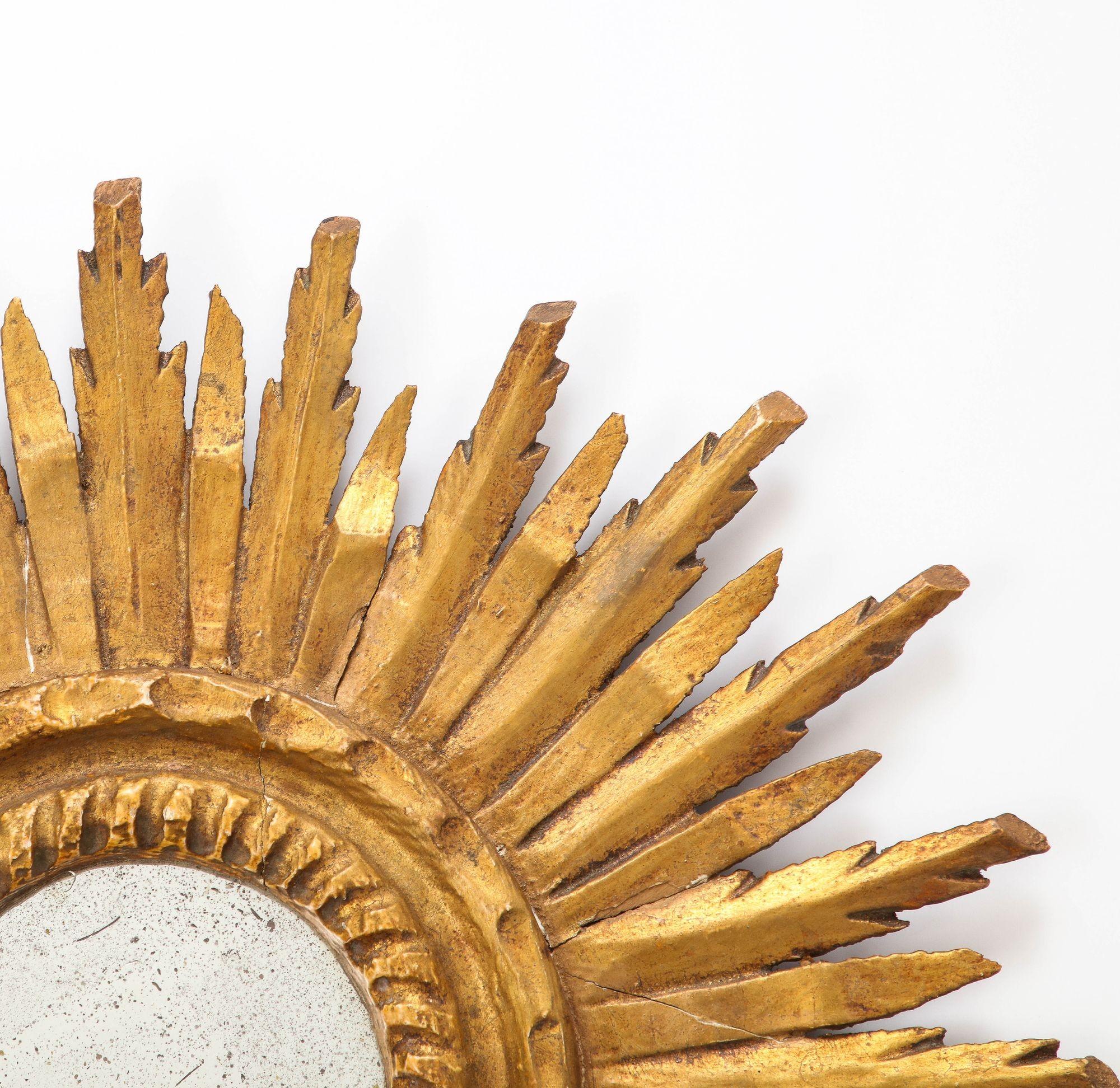 An early 20th century small French sunburst mirror. The classic sunburst frame is made of giltwood and has mirror plate with age appropriate patina. Wear consistent with age and use.