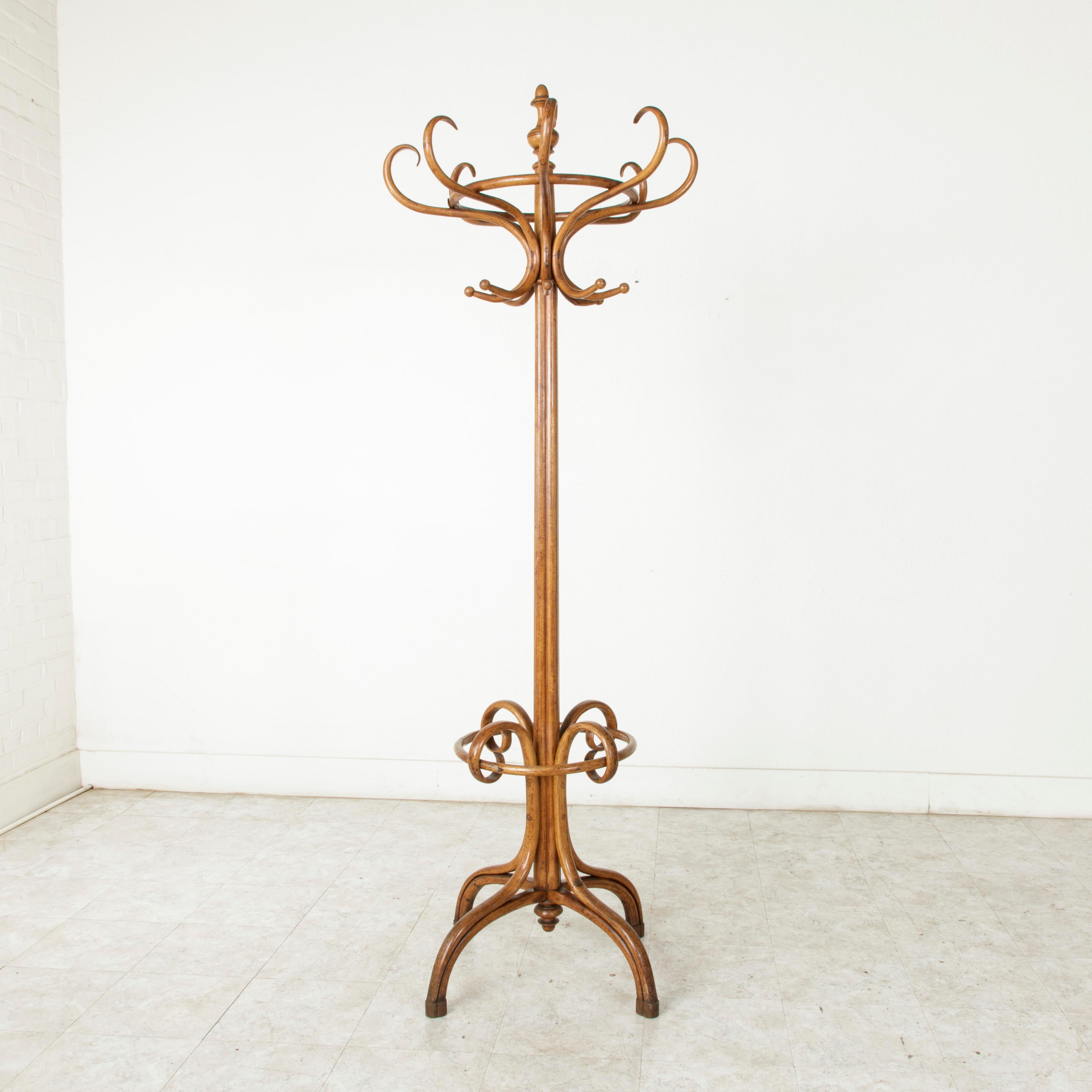 This classic Thonet style hat and coat rack or hall tree is made of richly finished bent beech wood. It features sixteen hat and coat hooks and an umbrella holder below. A familiar fixture in the turn-of-the-century French bistro, this piece will