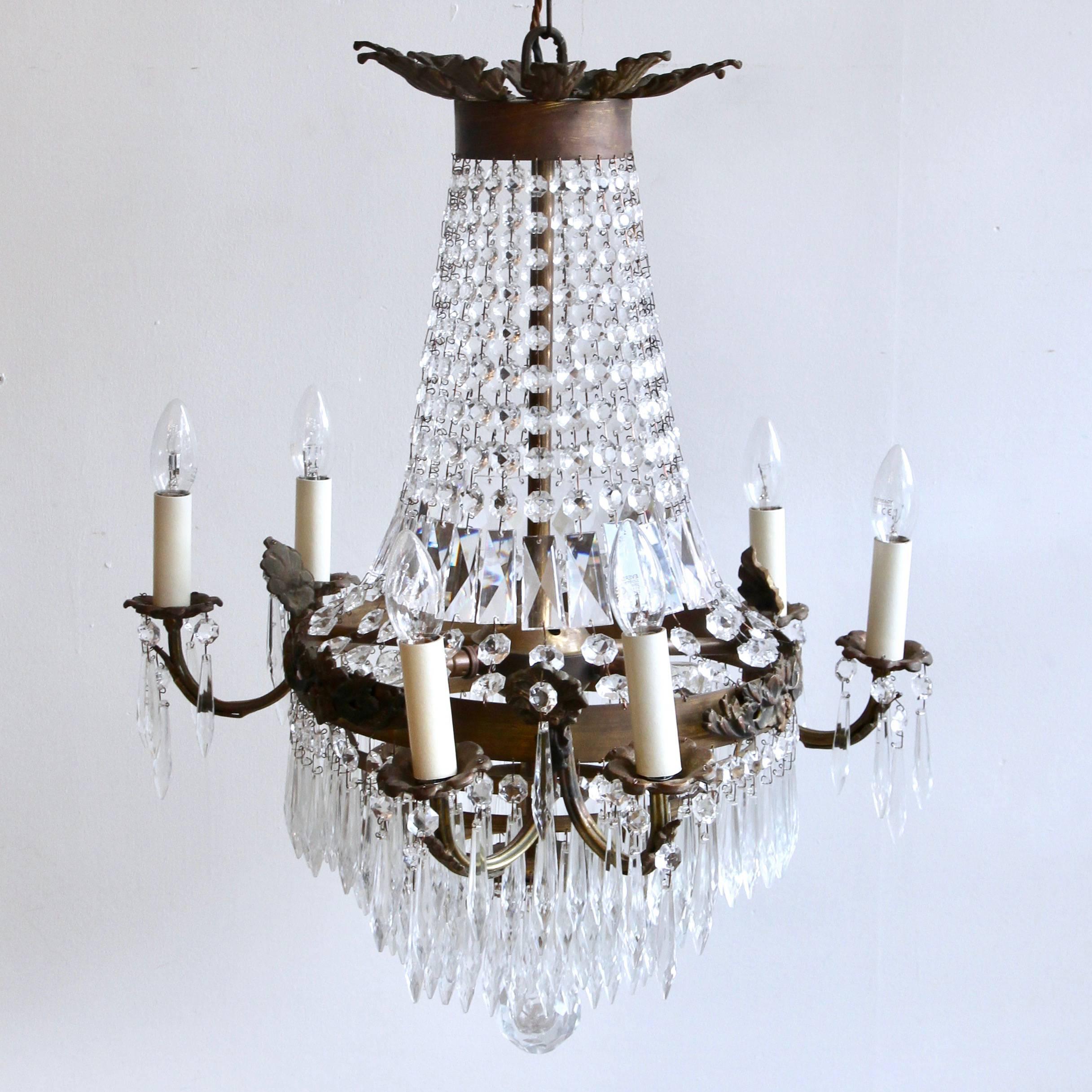 This French tiered and branch chandelier is a fine gilt early 20th century chandelier. The brass frame has formed a beautiful patina, shown especially in the moulded brass sconces on the outer top layer and the top crown brass leaf details. The