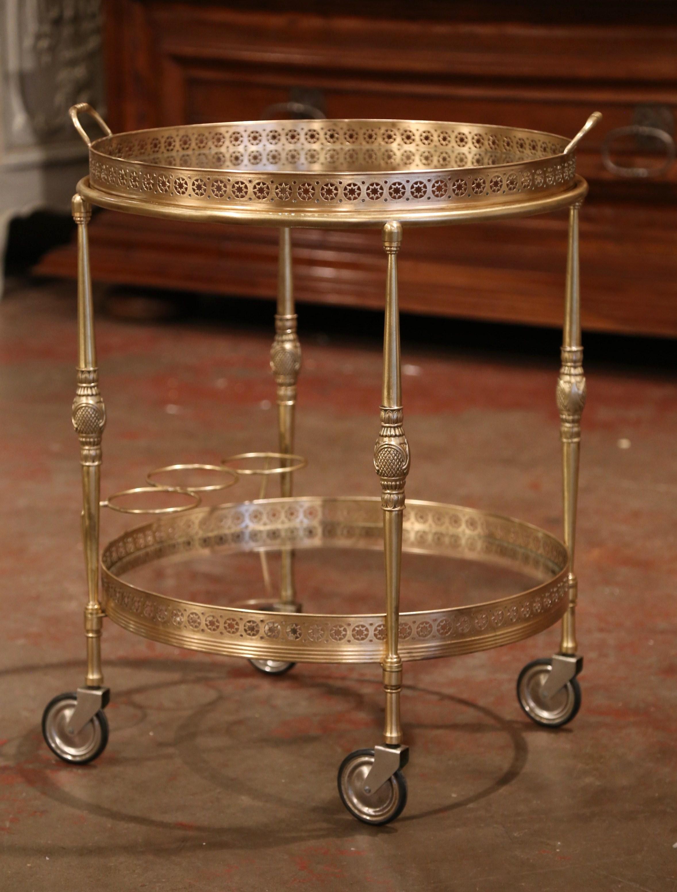 This elegant vintage rolling cart was created in France, circa 1930, the brass bar table stands on small round wheels over four turned legs decorated at the center. The cart features two plateaus both topped with glass surfaces, the top plateau