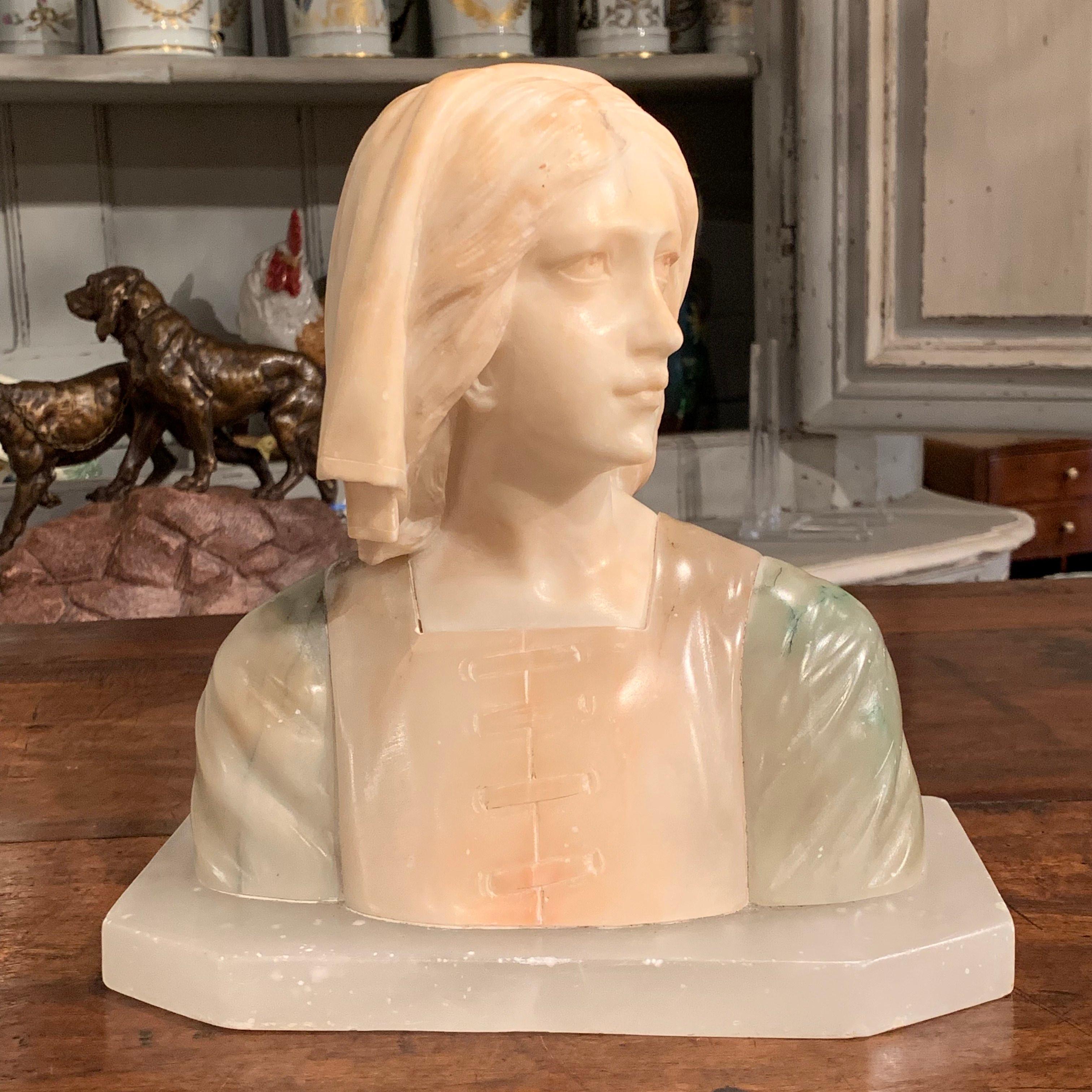 Decorate a shelf or desk with this antique, two-tone marble bust on flat base. Created in France circa 1920, the sculpture features a young woman looking to the side dressed in pre-20th century clothing and a head scarf. The body and base are both