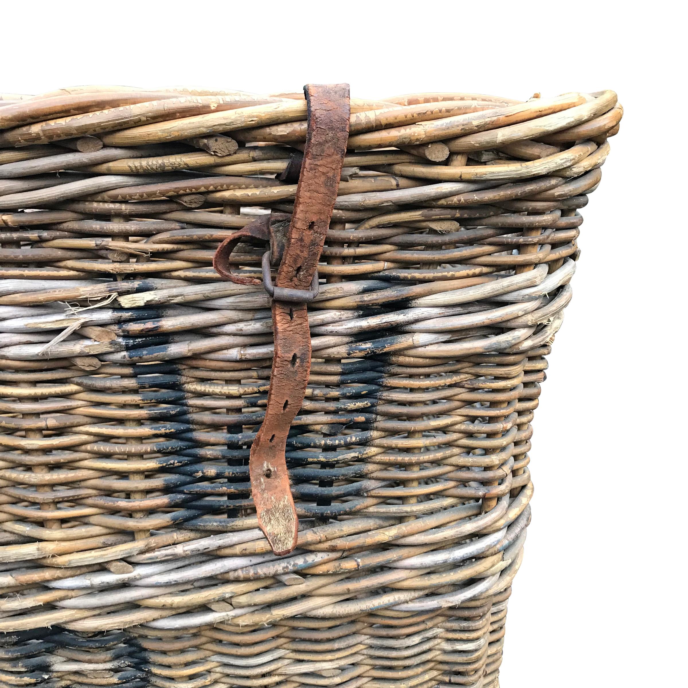 An early 20th century French vineyard handwoven basket, used to send grapes to press. The basket is painted with the initials of the vineyard, as well as the basket number. Original leather tie down straps remain. One handle is missing, and there