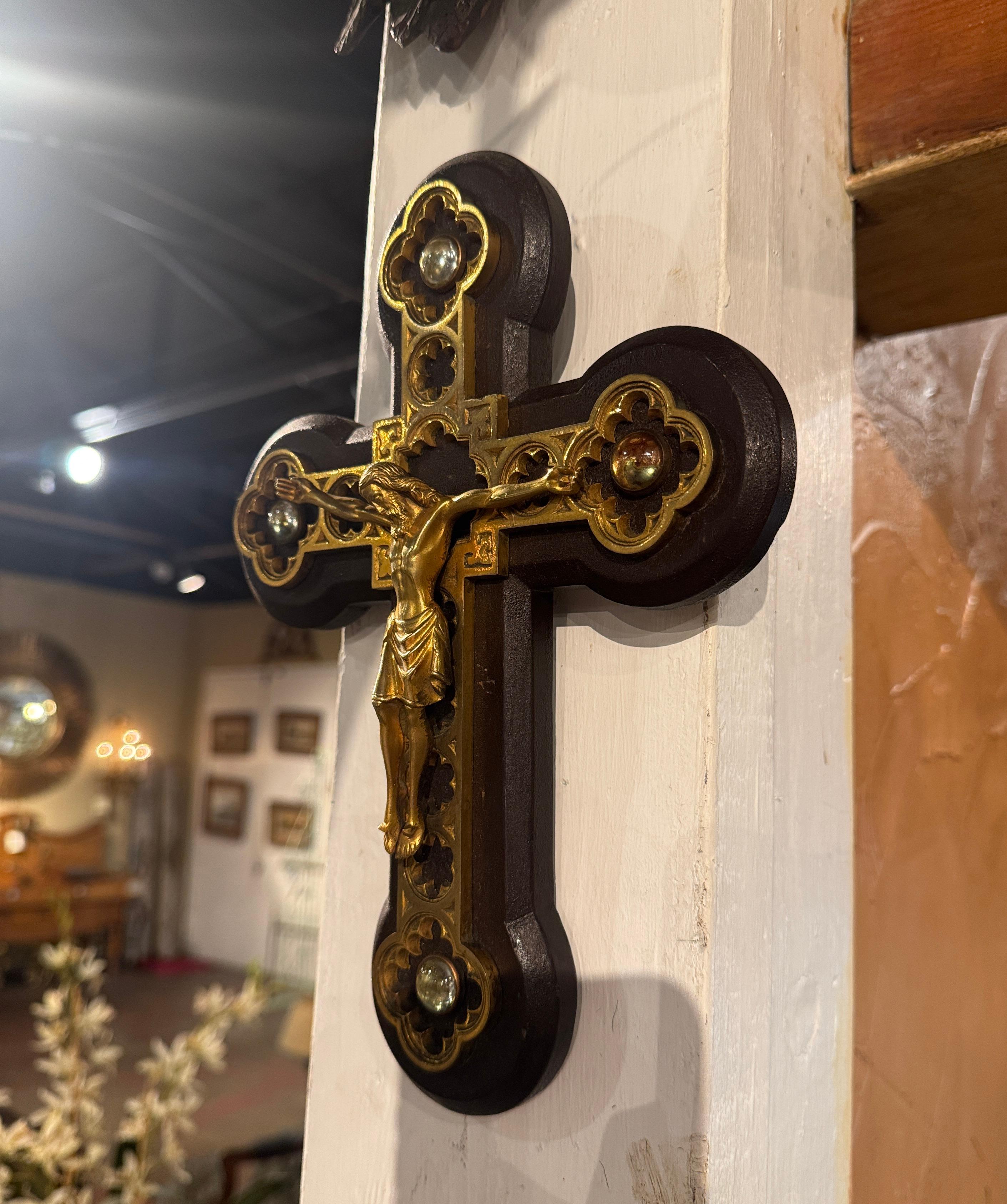 This beautiful and intricate crucifix was created in France circa 1930. This exquisitely  crafted crucifix, combines wood and brass in an intricate and elegant design. The wooden cross has rounded, clover-like edges, adding a decorative and ornate