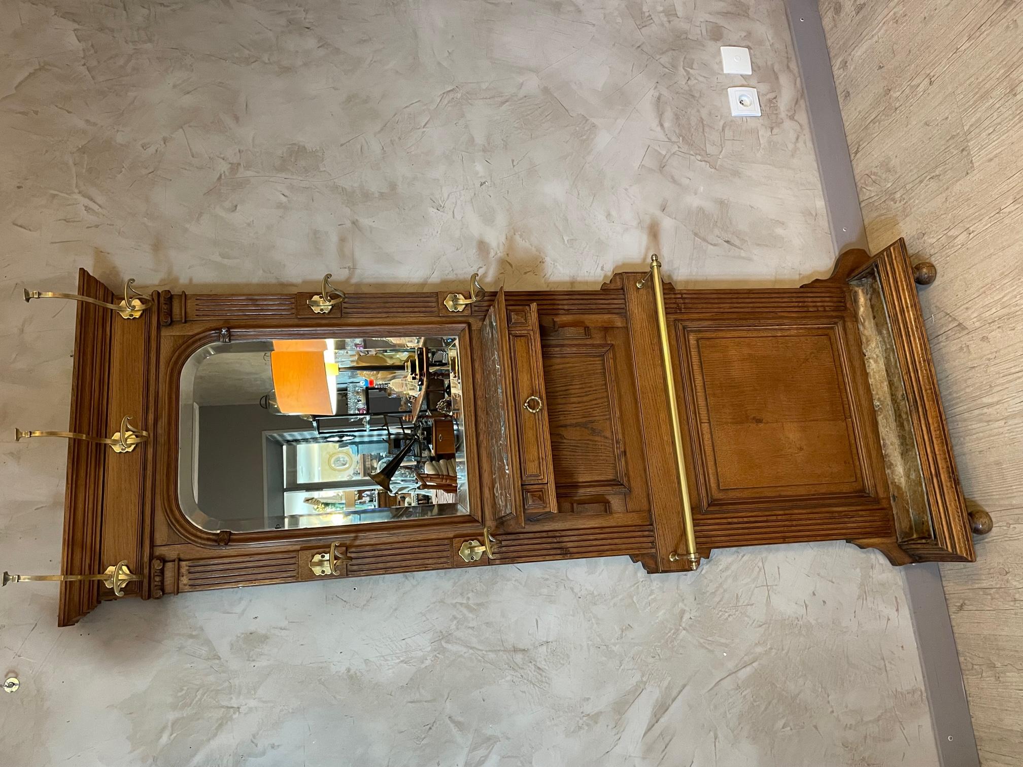 Very nice 1900 walnut coat hanger in very good condition. 
Brass coat rack and umbrella bar. Central drawer under a cherry marble top. Beveled rounded mirror. Zinc support at the bottom to collect the water from the umbrellas. Rare due to its