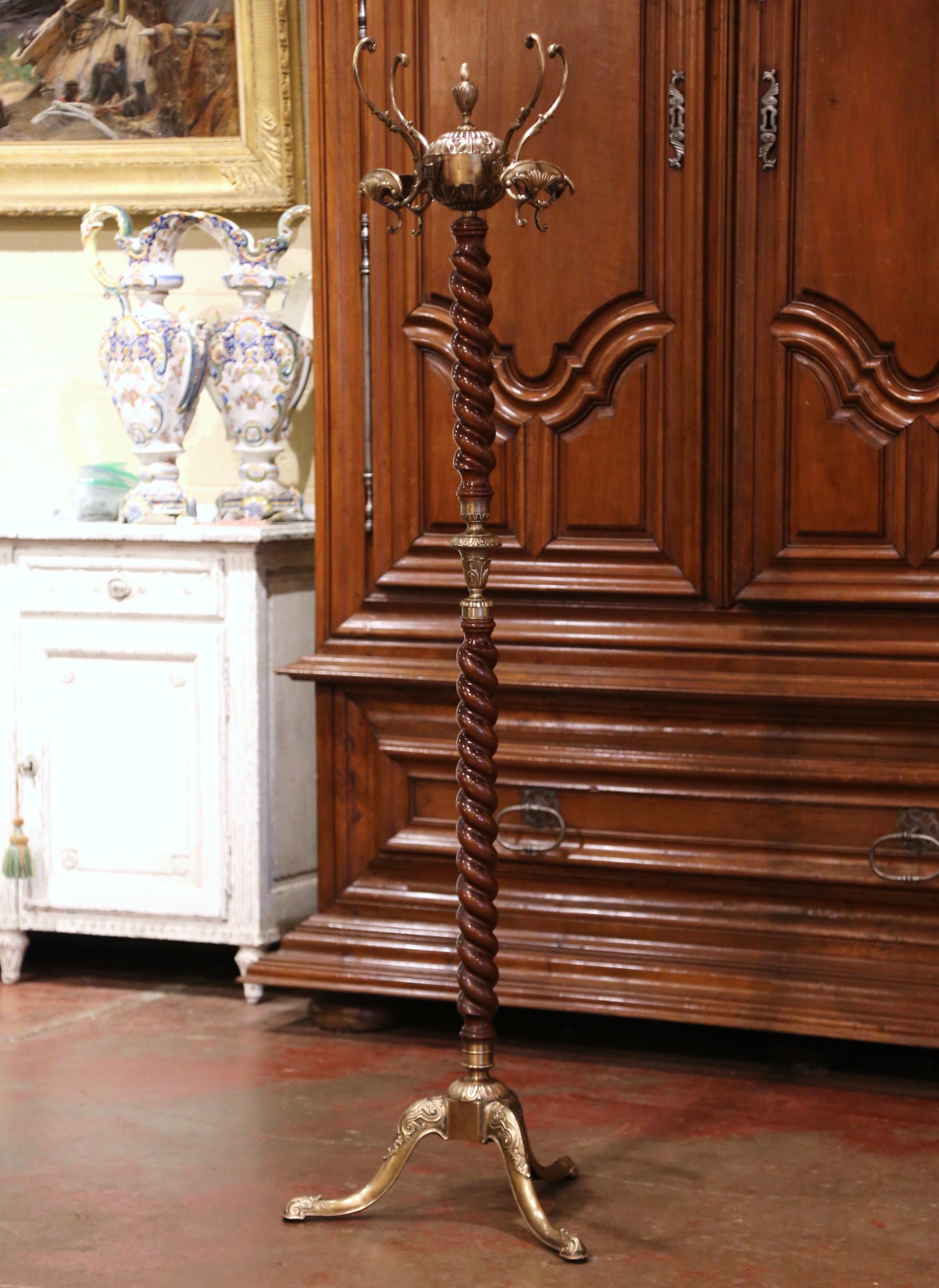 This antique carved fruit wood and brass hall tree was crafted in France, circa 1920. Standing on a wide tripod three curved legs ending with scrolled acanthus leaf motifs feet, the tall rack features a barley twist spiral central stem decorated