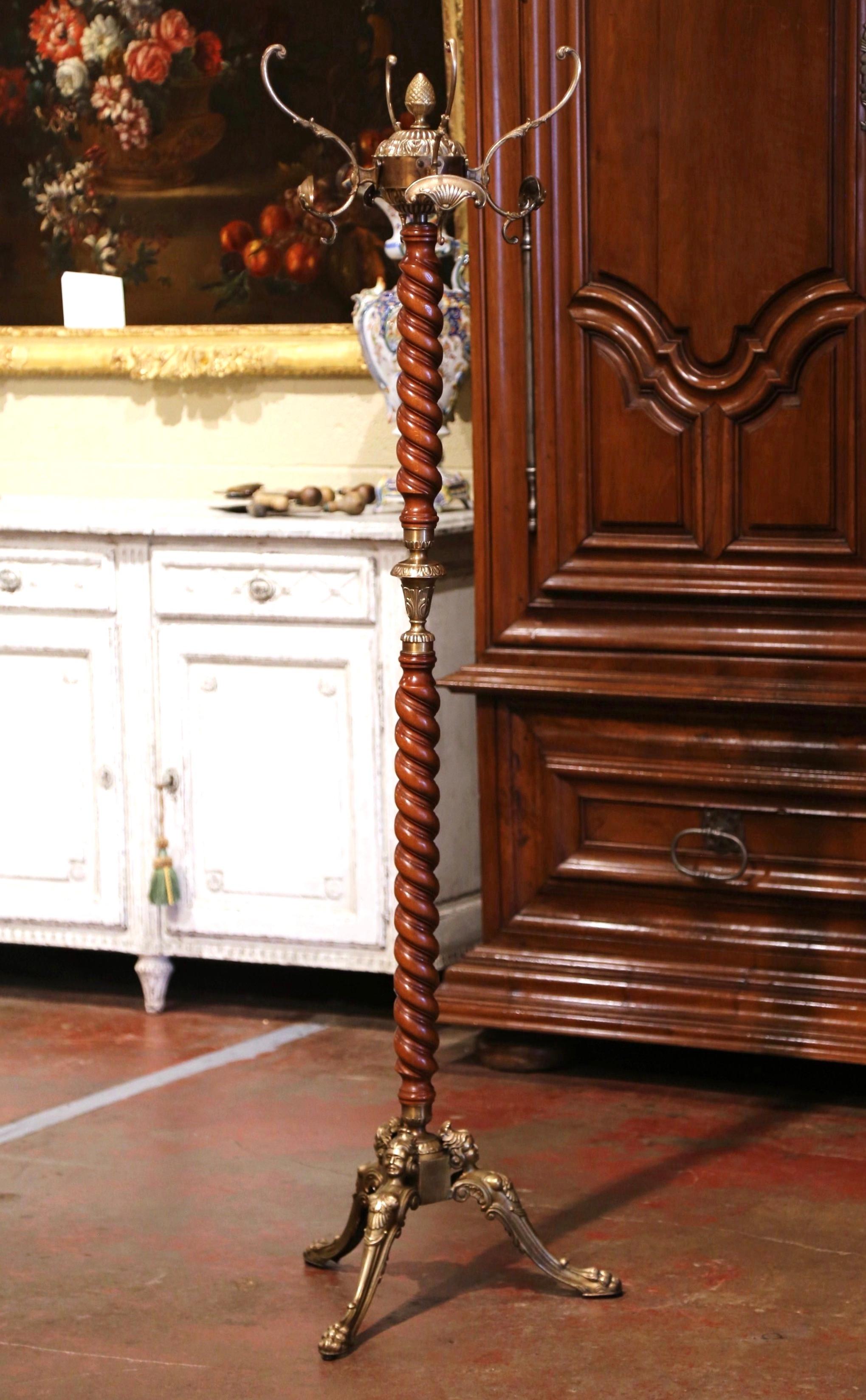 This antique carved fruit wood and brass hall tree was crafted in France, circa 1920. Standing on a wide three figural form legs ending with scrolled paw feet, the tall rack features a barley twist spiral central stem decorated with foliate motifs