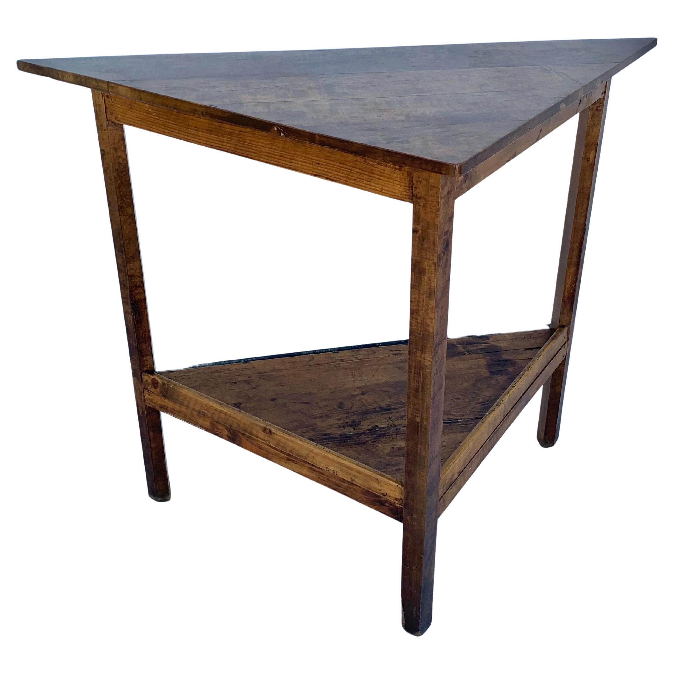 Trouvée dans le sud de la France, cette table d'angle française du début du XXe siècle a été fabriquée à la main en noyer ancien au début des années 1900. La pièce présente un design triangulaire à deux niveaux, dans un souci de gain de place et de