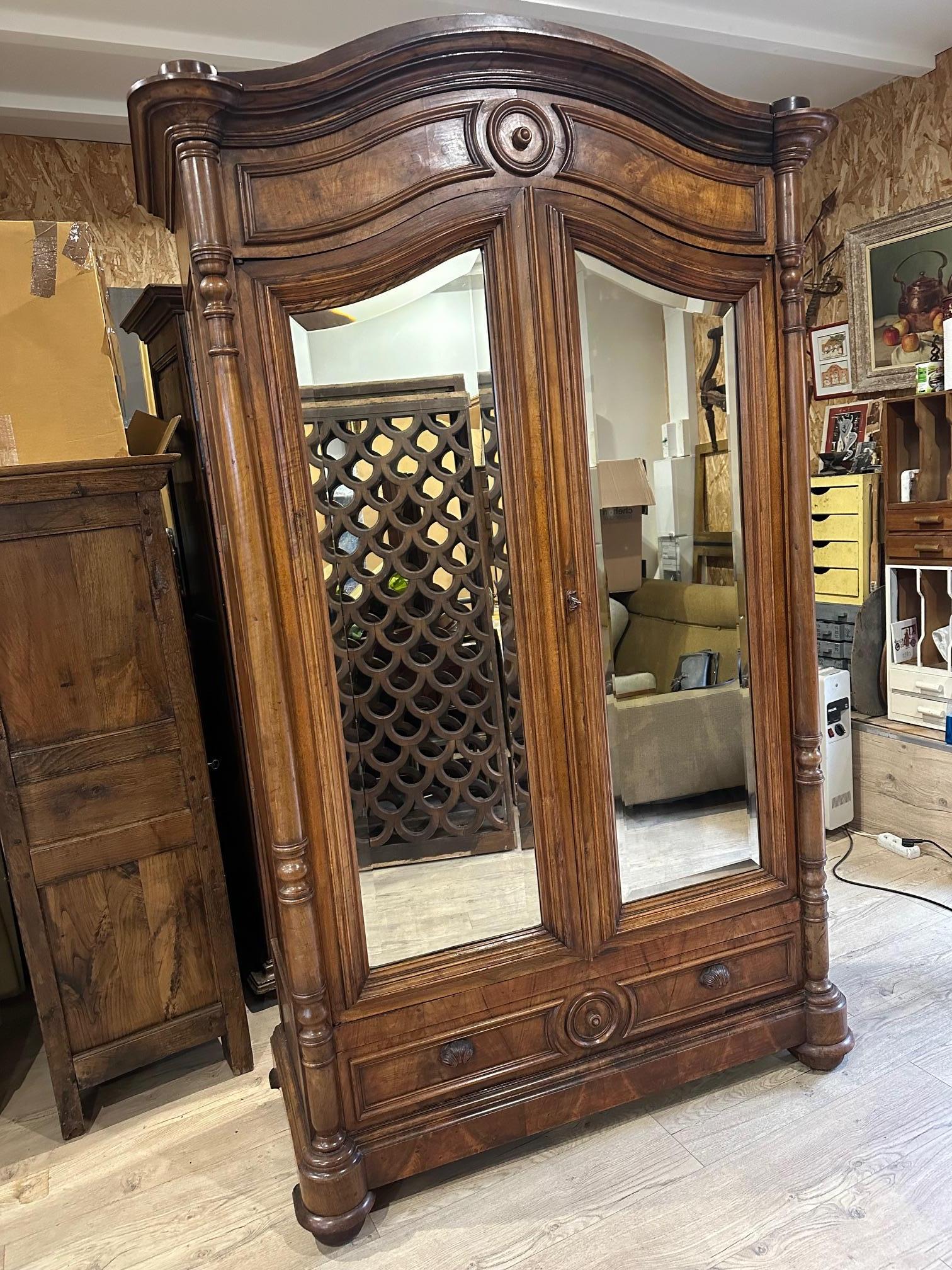Very beautiful high quality walnut mirror wardrobe dating from the beginning of the 20th century (1900s).
Fully removable. Four modular shelves to suit your convenience.
Two doors with beveled glass mirrors. Large drawer with two shell handles.