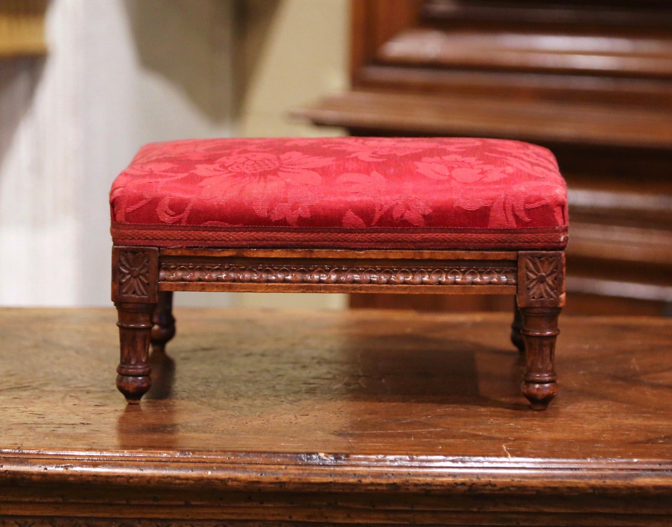 Put your feet up with style and comfort with this elegant Louis XVI foot stool. Crafted in France circa 1920 and rectangular in shape, the antique stool stands on tapered legs over a carved apron decorated with rosette medallions in each corner. The