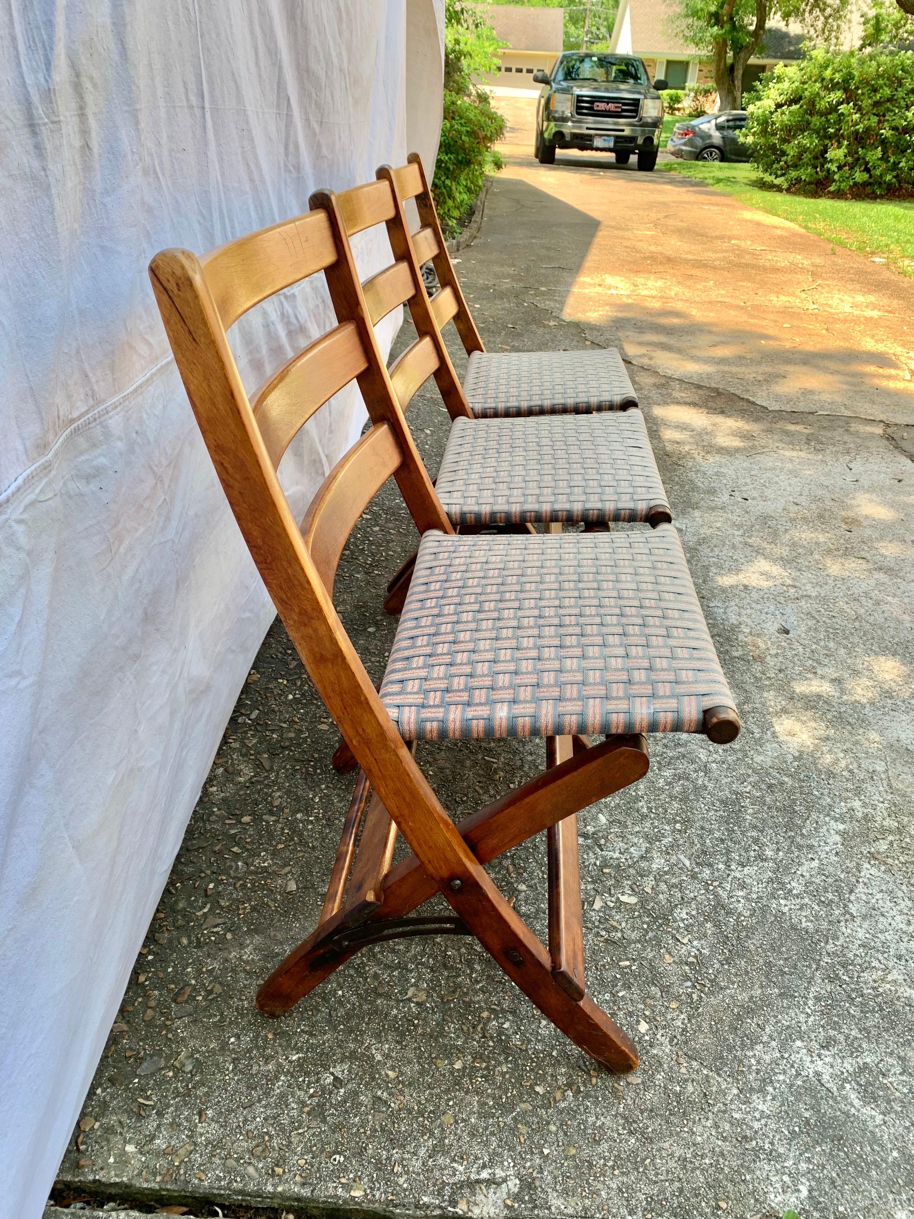 Trouvé dans le sud de la France, ce banc pliant a été fabriqué en noyer au début des années 1900. La pièce est conçue avec un dossier à lattes continues et trois sièges rembourrés en tandem qui se soulèvent en position verticale. L'ensemble du banc,