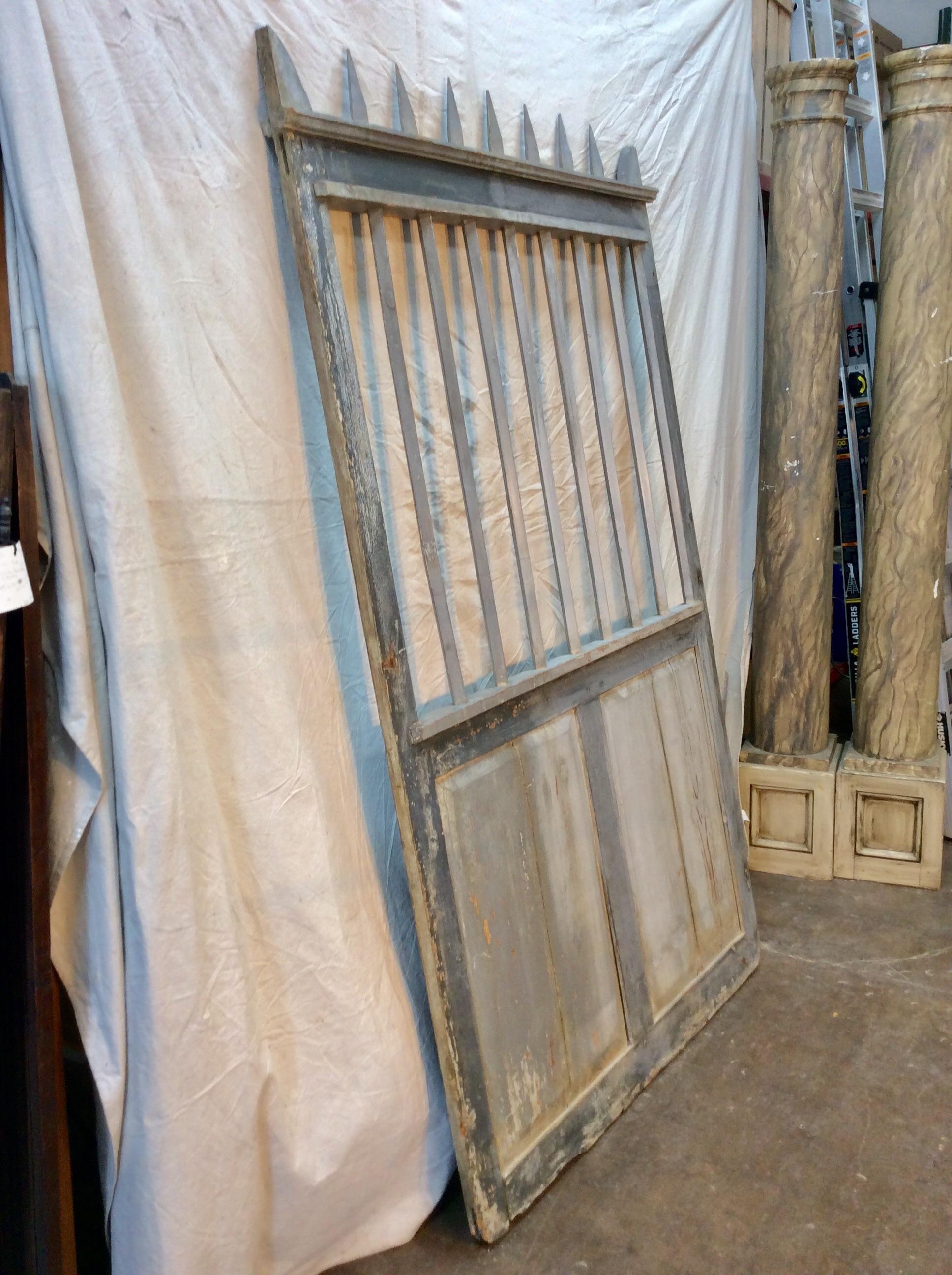 Found in the South of France, this Early 20th Century French Wood Gate is crafted with a solid bottom panel and bars at the top that end in a pointed fashion. Featuring a warm painted patina in French blues and grays, this piece could be used