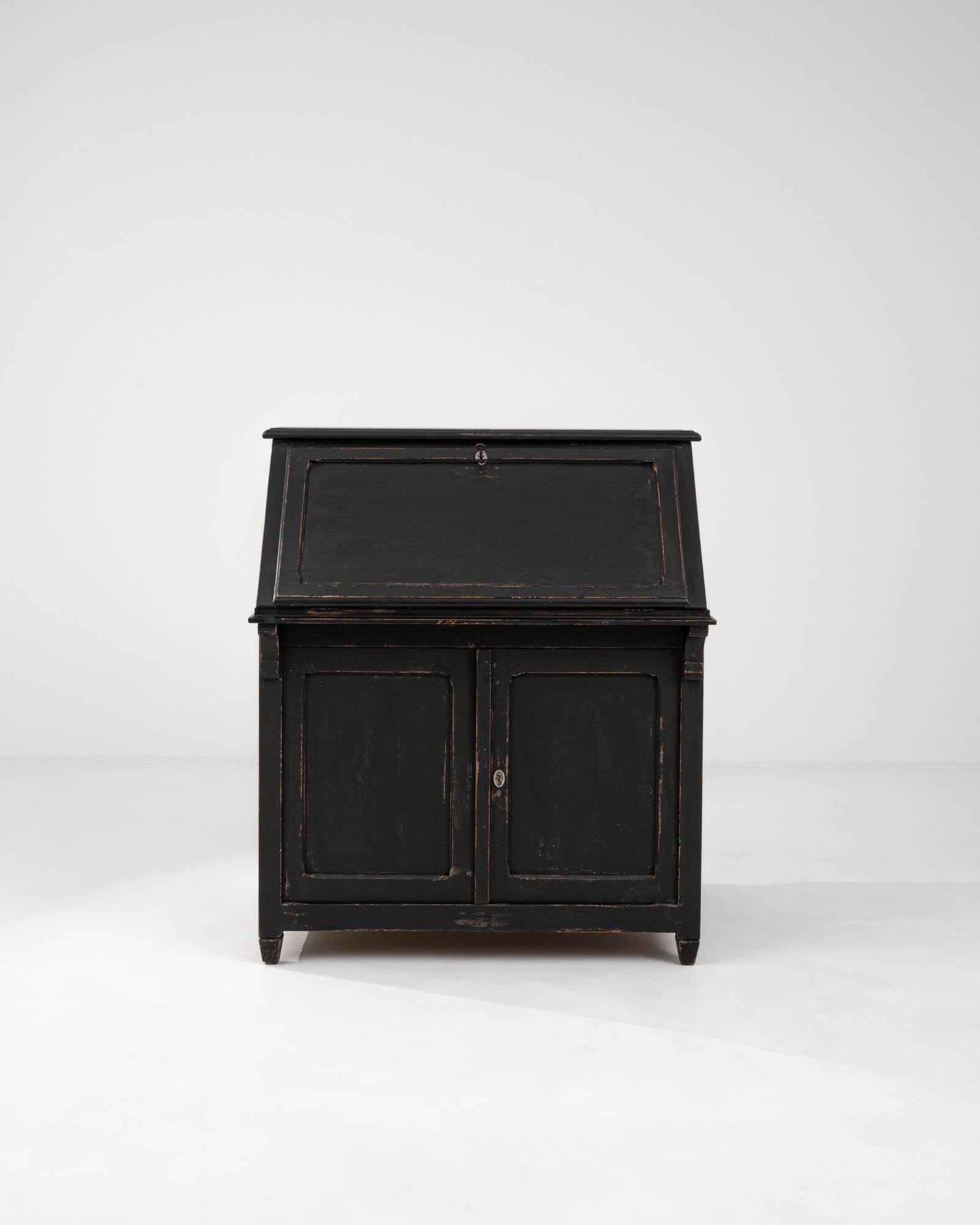 This early 20th-century French wood patinated desk exemplifies classic charm and functional design. Its unique architectural form, reminiscent of a stately structure, is accentuated by a deep black patina that highlights the edges and contours,