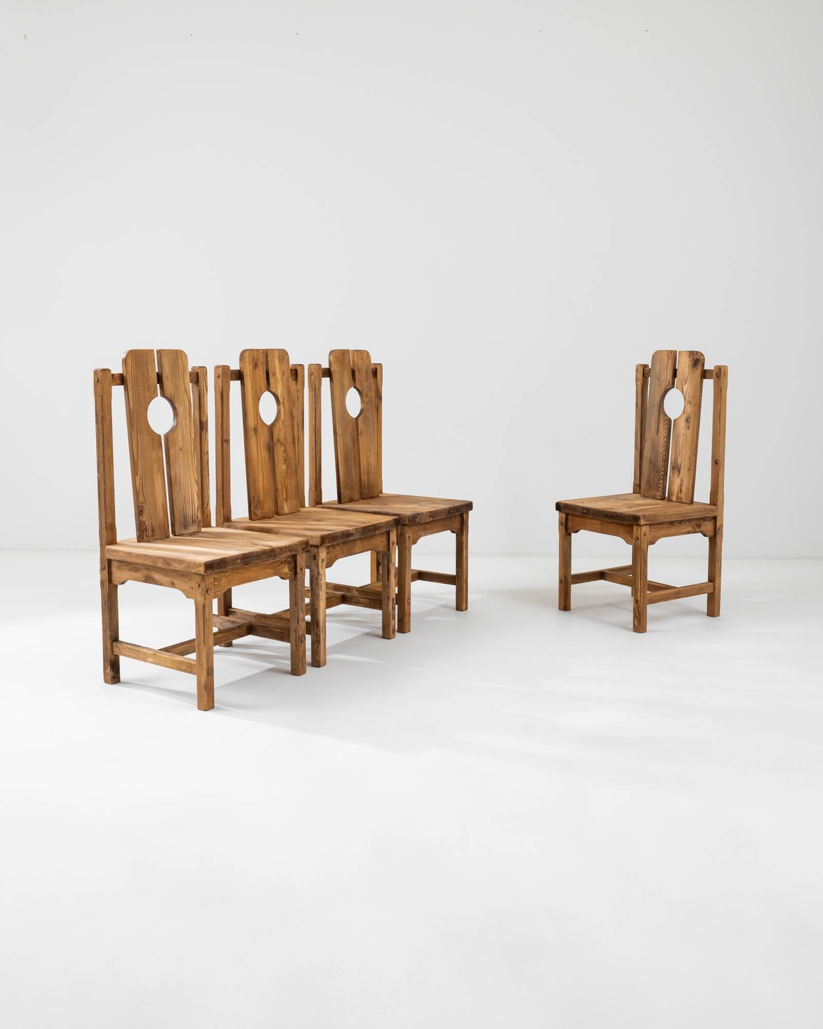 A set of wooden dining chairs created in early 20th century France. This set of unique dining chairs exudes a woodsy, brutalist charm, with warm and bright wood and minimal design details. Two rounded planks rest side by side to form a neat circle
