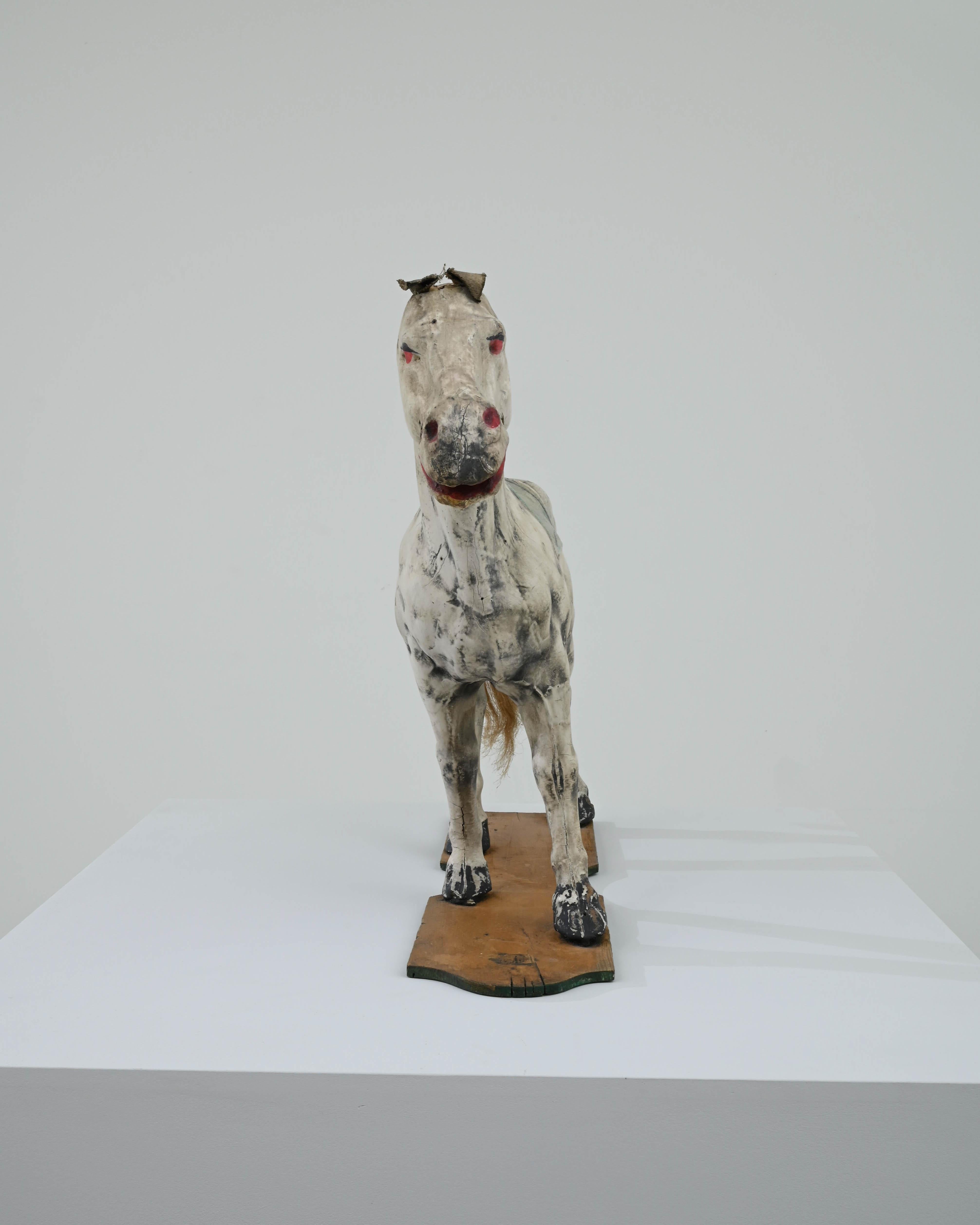 A wooden decorative sculpture of a horse created in early 20th century France. Playfully painted, and caught mid-pose, this charming horse exudes a sense of gracefully decorative flair. The posture of the horse communicates a contrapposto pose, as