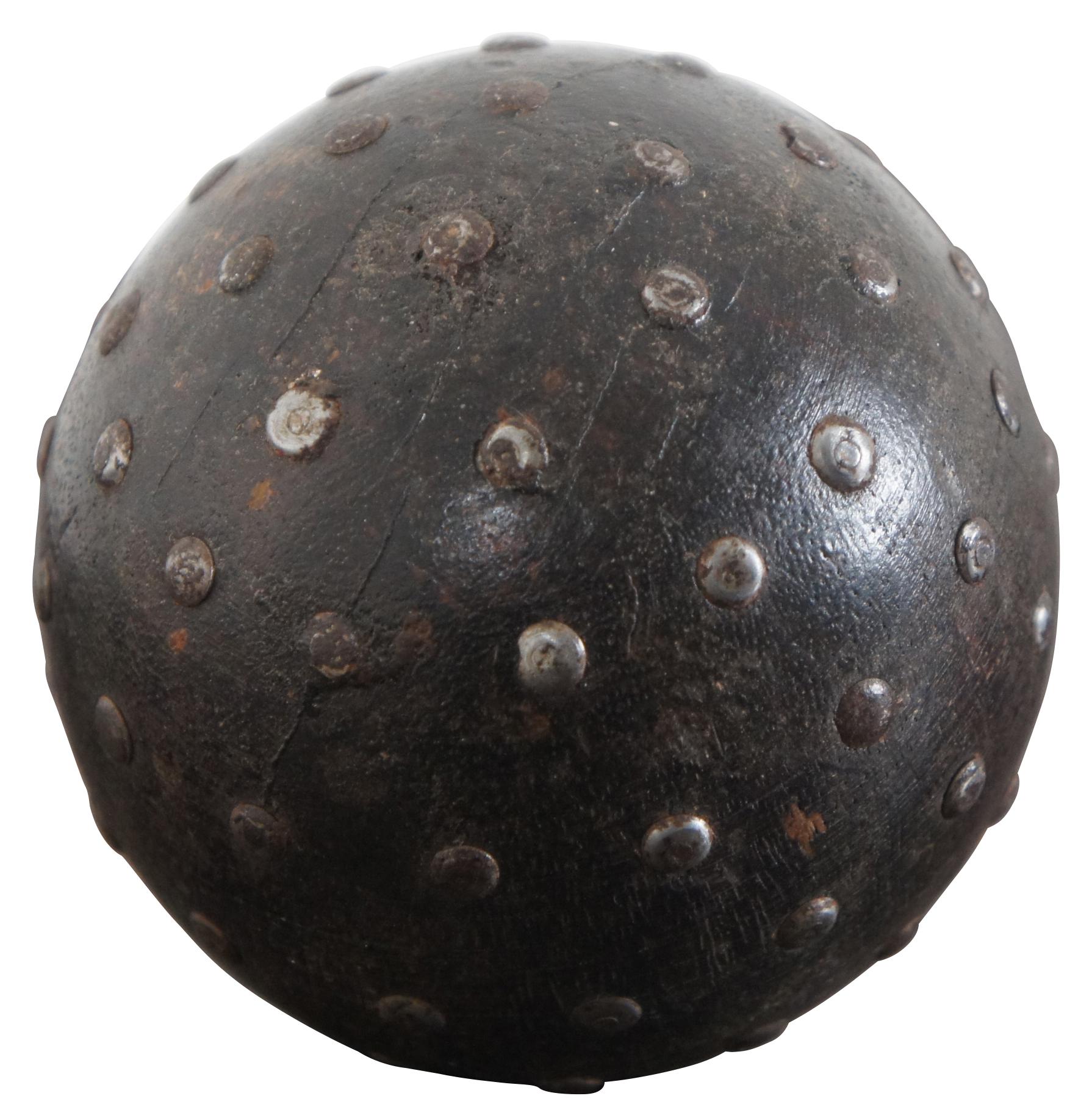 Vintage wooden ball partially studded with nails and painted brown.
 