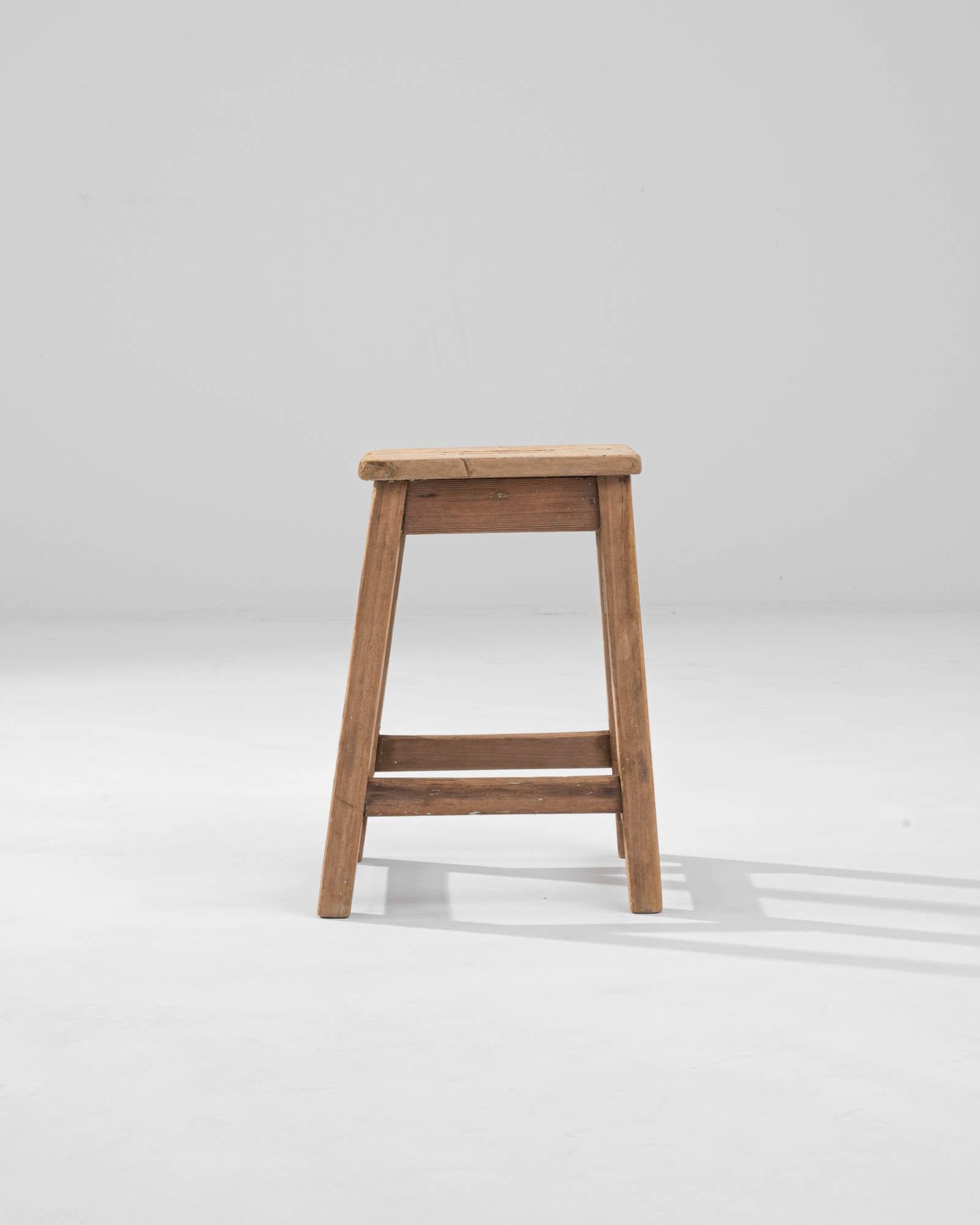 Introducing a piece that's as much a charming slice of history as it is a practical seating option – the Early 20th Century French Wooden Stool. Crafted from solid wood, this stool exhibits the warmth and resilience of a bygone era with its