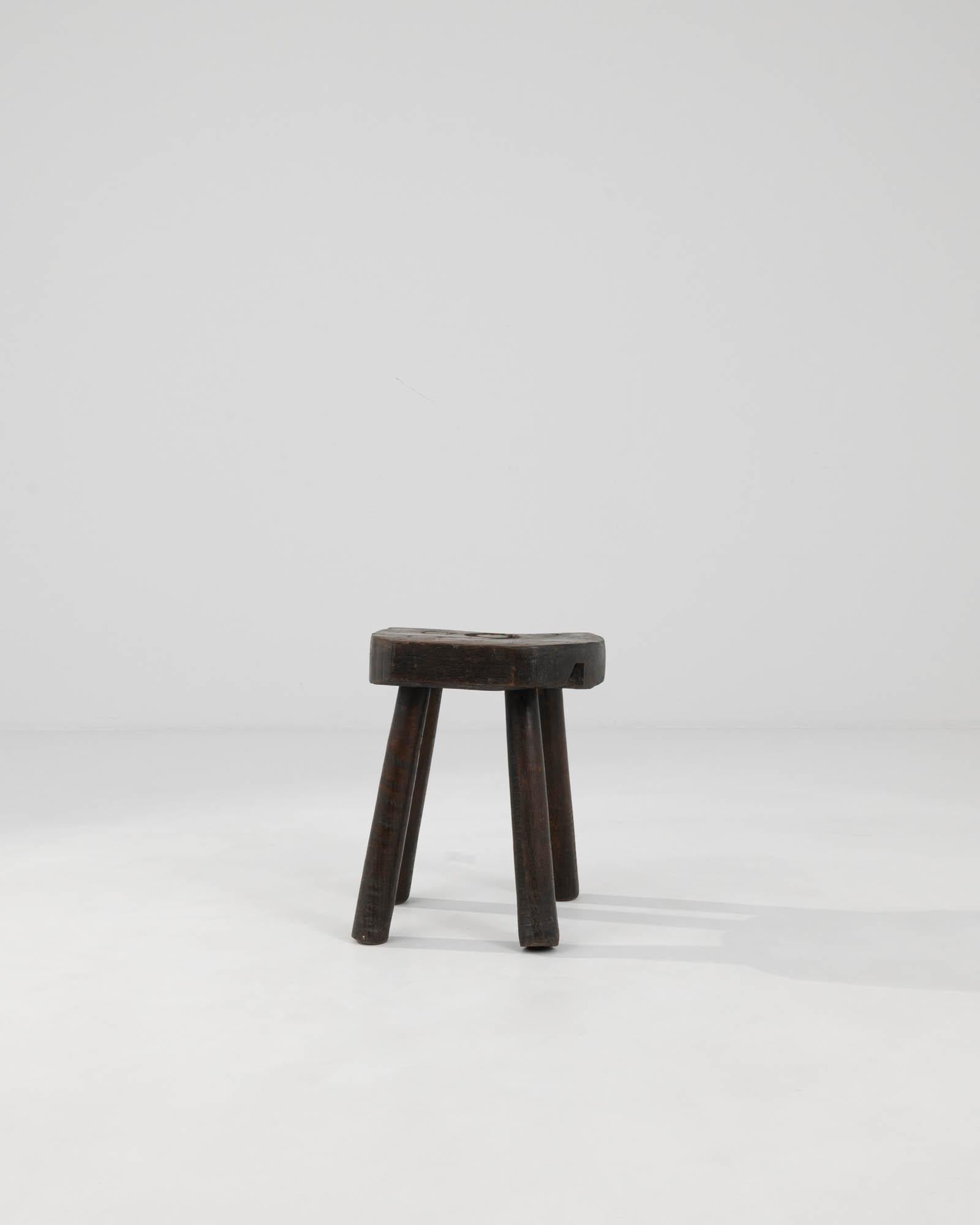 Discover the charm of rustic French décor with this Early 20th Century French Wooden Stool, a genuine artifact that radiates a rich sense of history. This robust piece is beautifully crafted from solid wood, featuring a dark patina that tells a