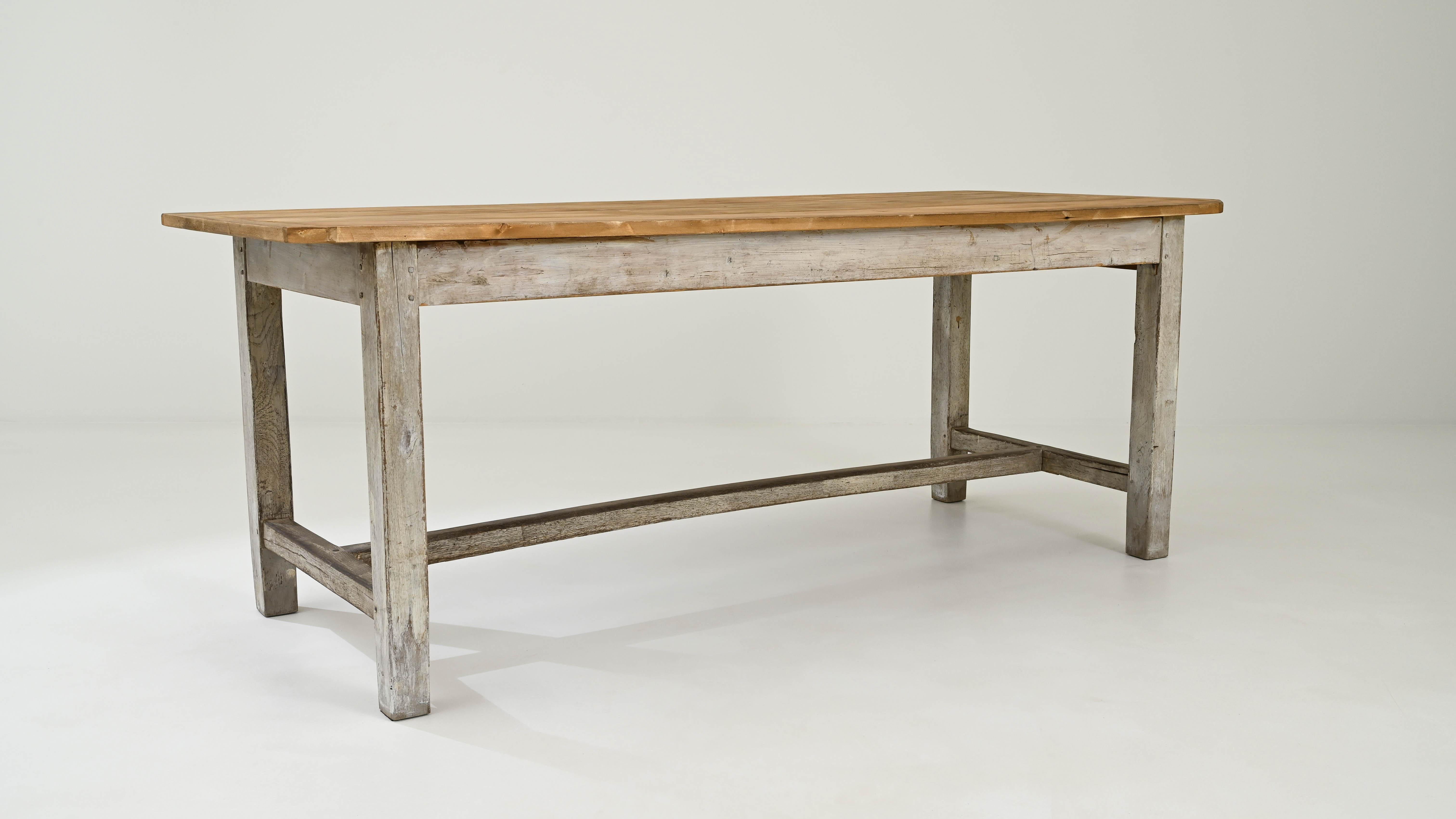 This early 20th Century French Wooden Table effortlessly merges timeless design with a unique blend of light wood throughout, culminating in a distinctive tabletop with a warm, rich finish. Crafted with meticulous attention to detail, the table