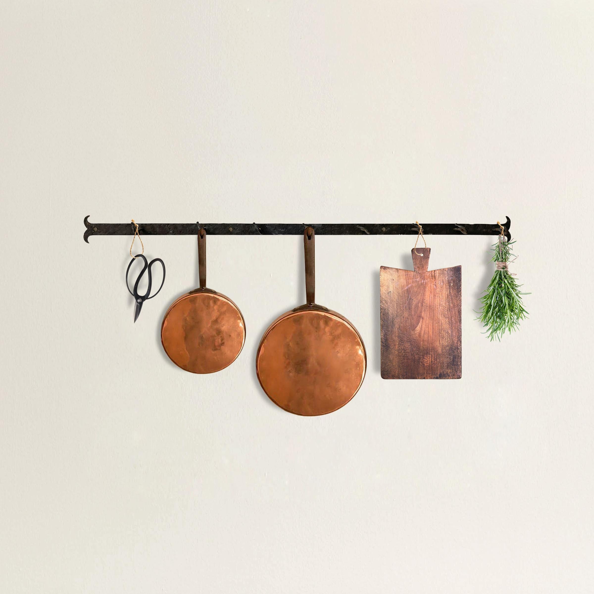 A simple yet refined early 20th century French wrought-iron wall-mounted pot rack with eight hooks. Perfect for hanging on the wall above your stove to keep pots, lids, cutting boards, or any myriad things at your finger tips in the kitchen.