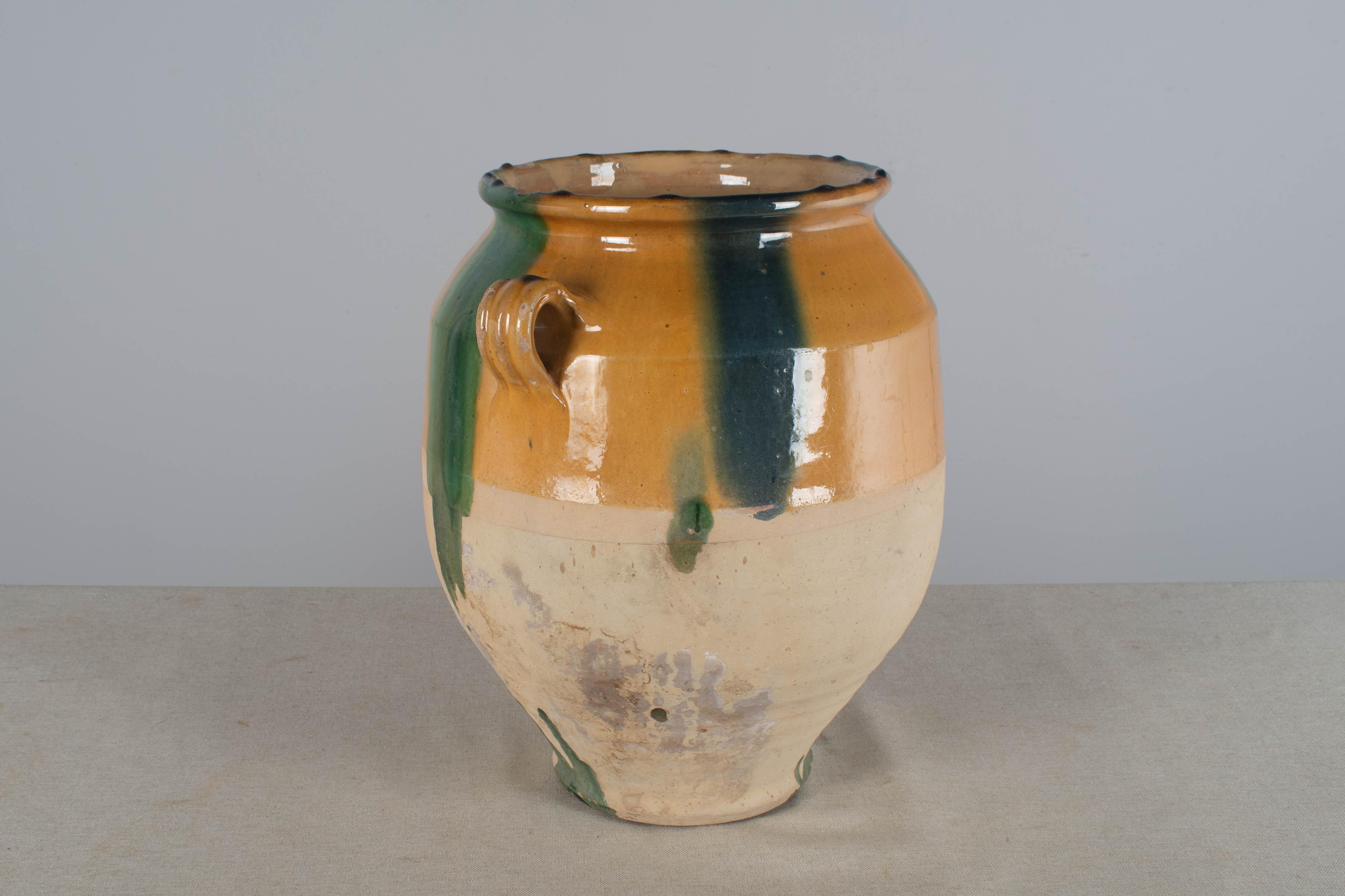 A 20th century French earthenware confit pot with traditional yellow glaze and some blue and green drips. Minor chips at the rim. These ordinary earthenware vessels were once used daily in the French country home and have beautiful rustic glazes of
