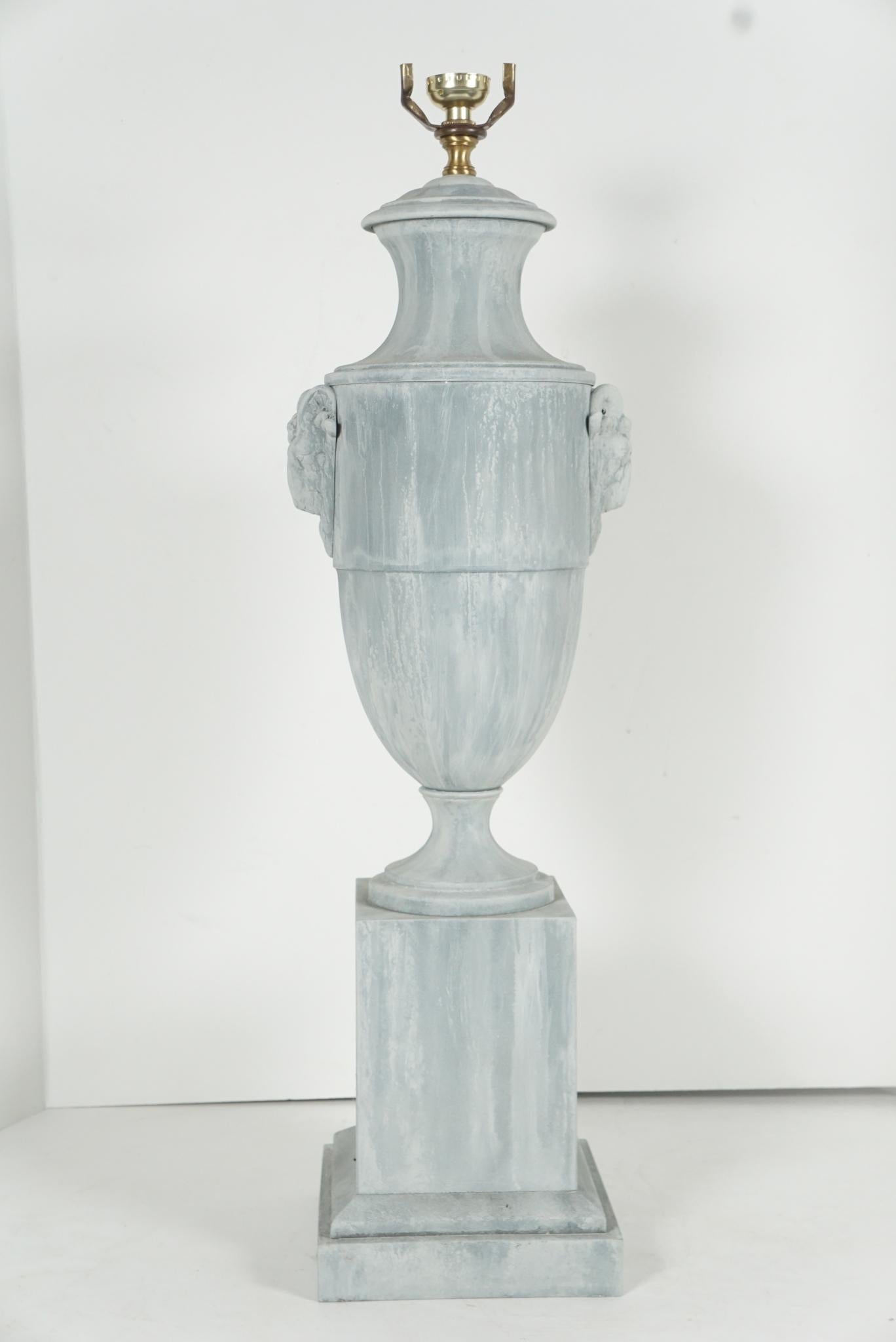 This urn made in France was produced as a decorative object circa 1920. Designed as a Louis XVI style urn with classical rams head handles the large-bodied urn rests on a raised block set up on a stepped base. Once possibly painted in a marbled
