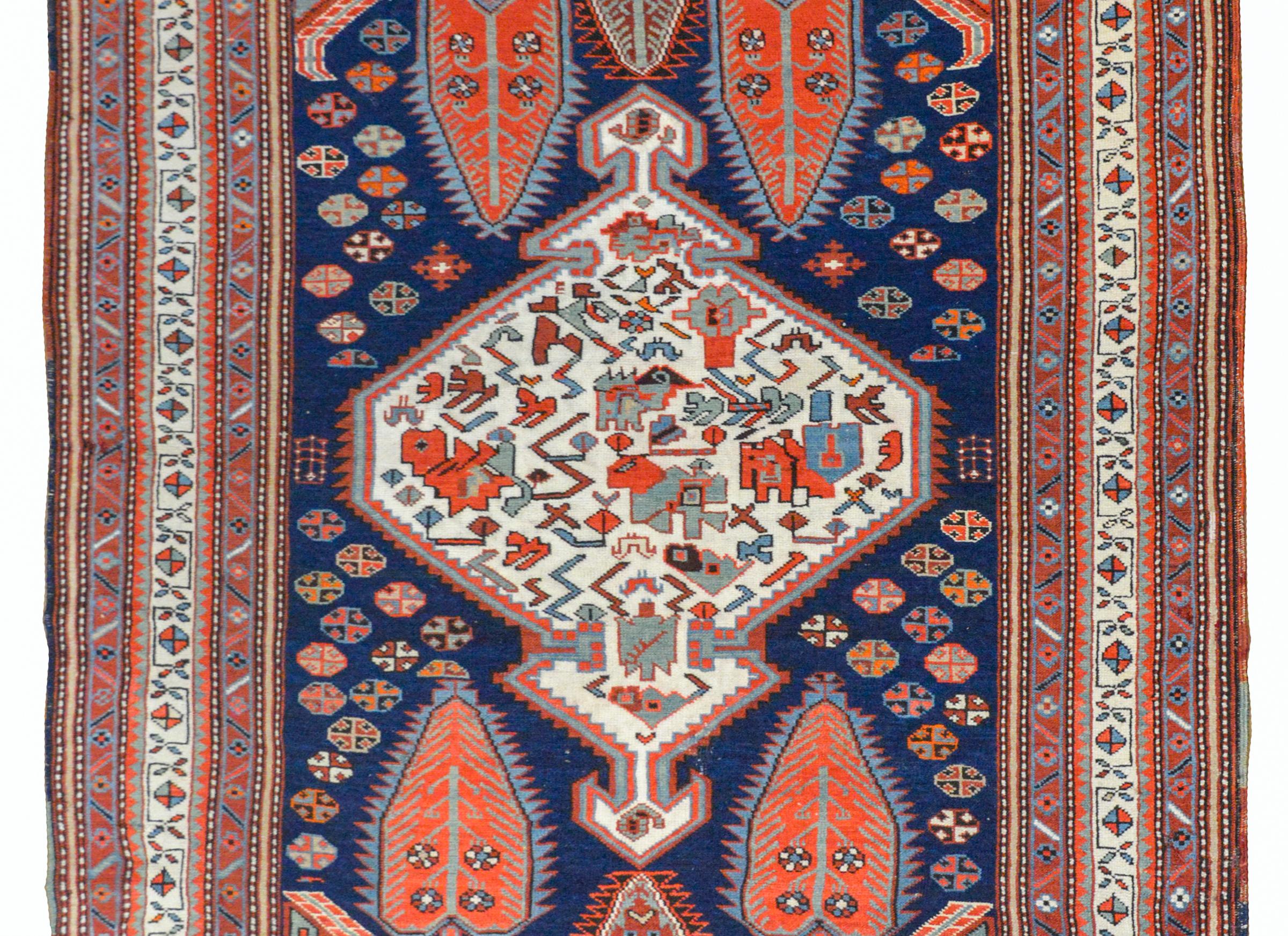 A fantastic early 20th century Shkli rug from the Karabagh area in the Caucasus with a bold tribal pattern with a large white diamond medallion with stylized flowers and vines woven in crimson, green, indigo, and white all set against an indigo