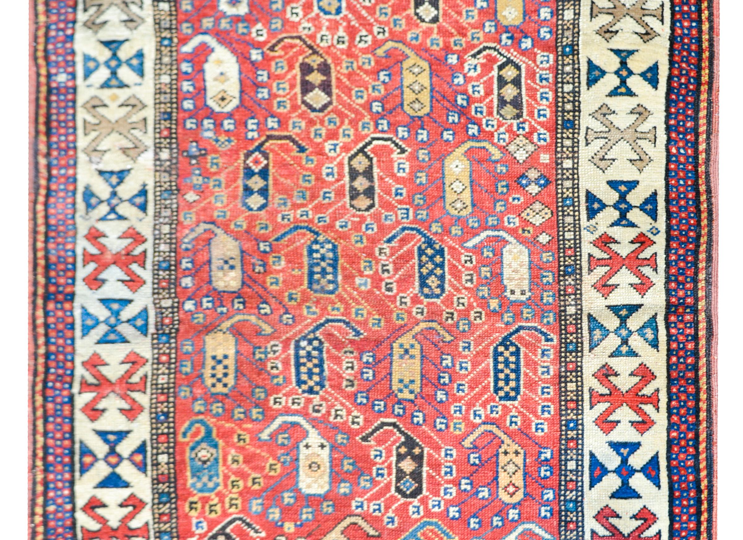 An incredible early 20th century Azerbaijani Ganjeh rug with an all-over multi-colored paisley pattern across the field set against an abrash crimson background, and surrounded by a beautiful stylized floral patterned border with a petite geometric