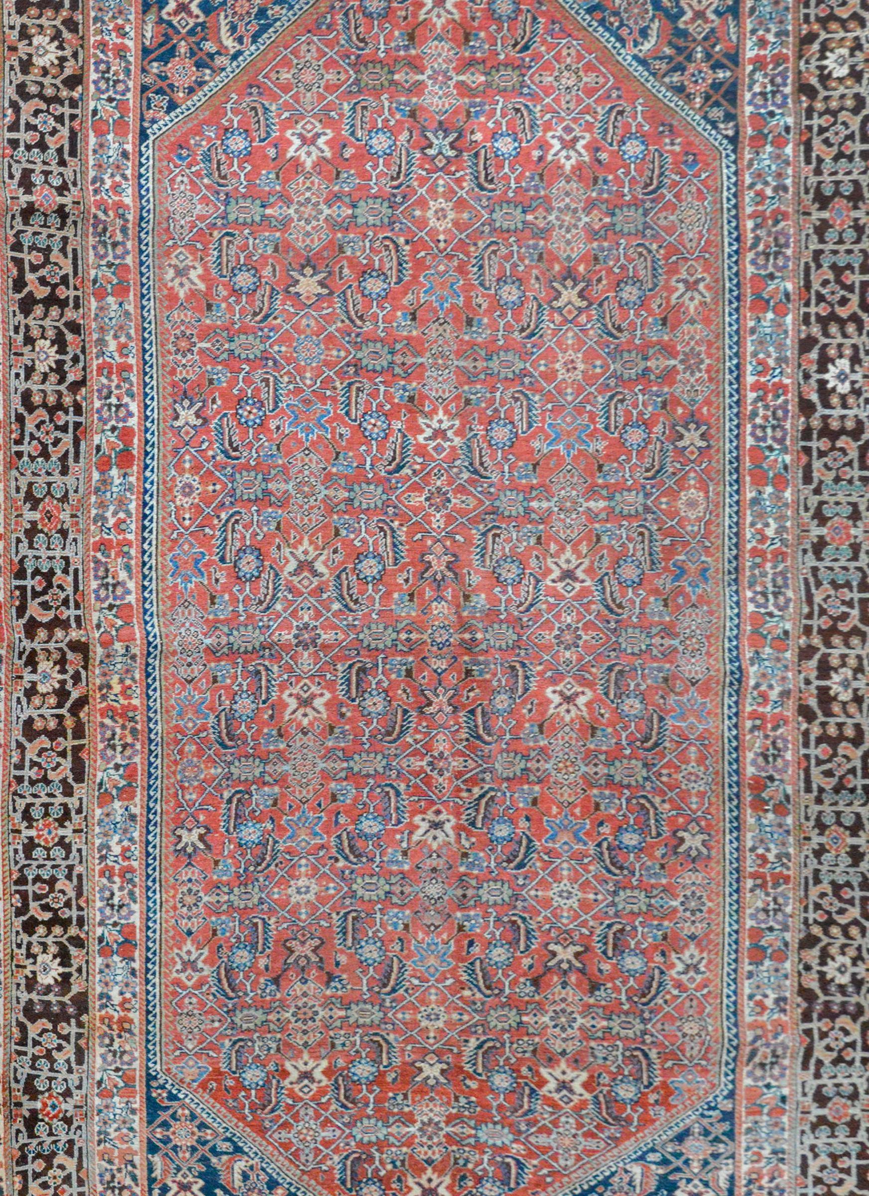 A beautiful early 20th century Persian Gashgaei rug with an all-over floral trellis pattern woven in crimson, light and dark indigo, white, and pale green colored vegetable dyed wool, all against a crimson background. The border is beautiful, with a