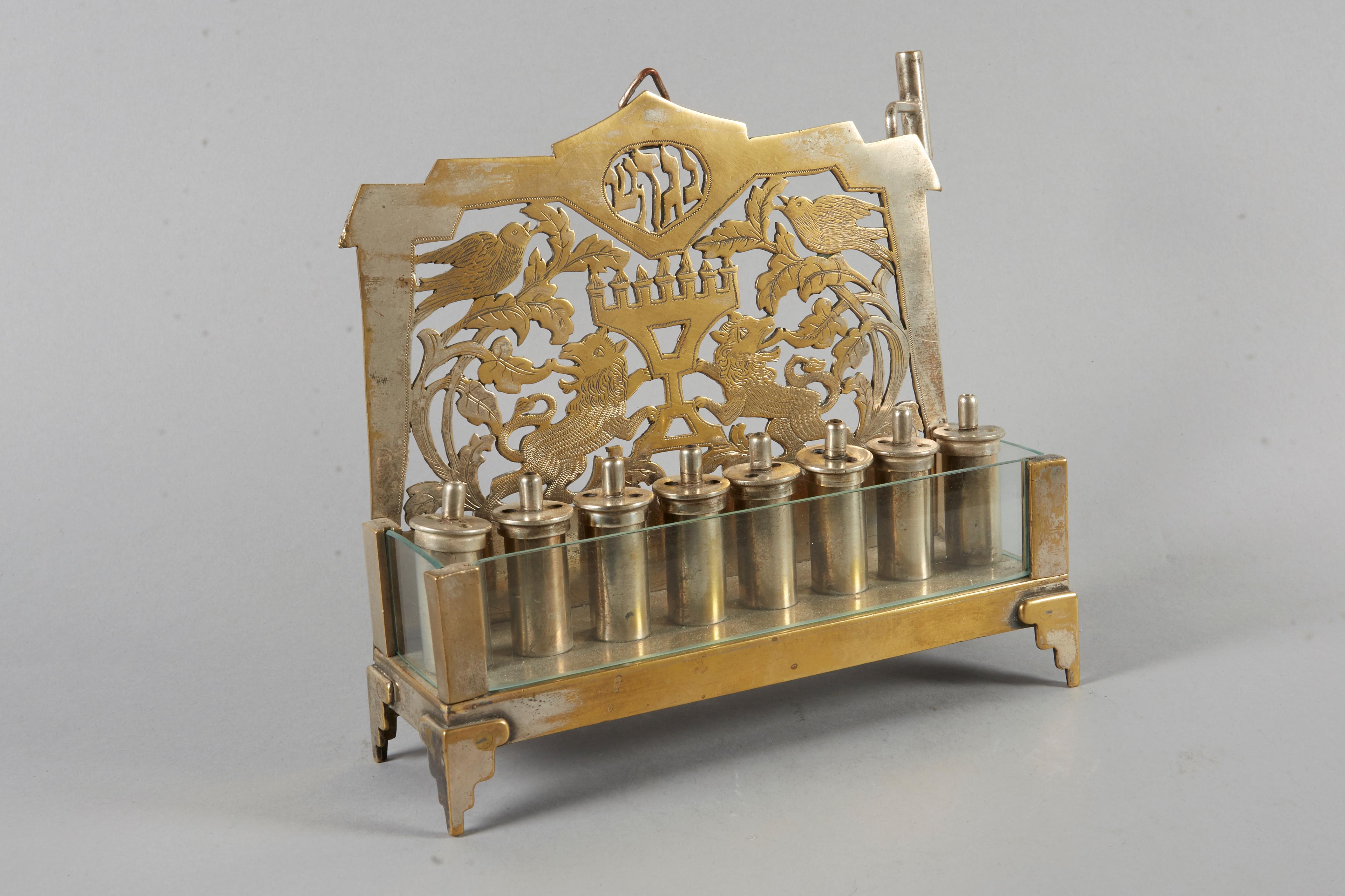 Unique and rare Hanukkah Lamp Menorah, brass and glass, Germany, circa 1900.
Hand cutout and engraved backplate with two lion flaking at the Temple Menorah surrounded with floral decoration and birds. Topped with Hebrew letters for: Great Miracle