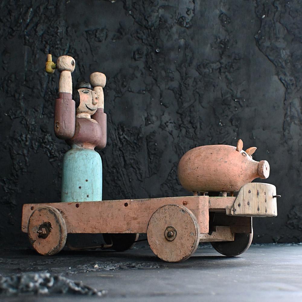 Early 20th Century German Folk Art Animated Pull Along Toy 

A fun, authentic example of an early 20th Century folk art child’s pull along toy. This animated toy works when the wheels turn, the pig jumps forward as the farmers wife chases him with
